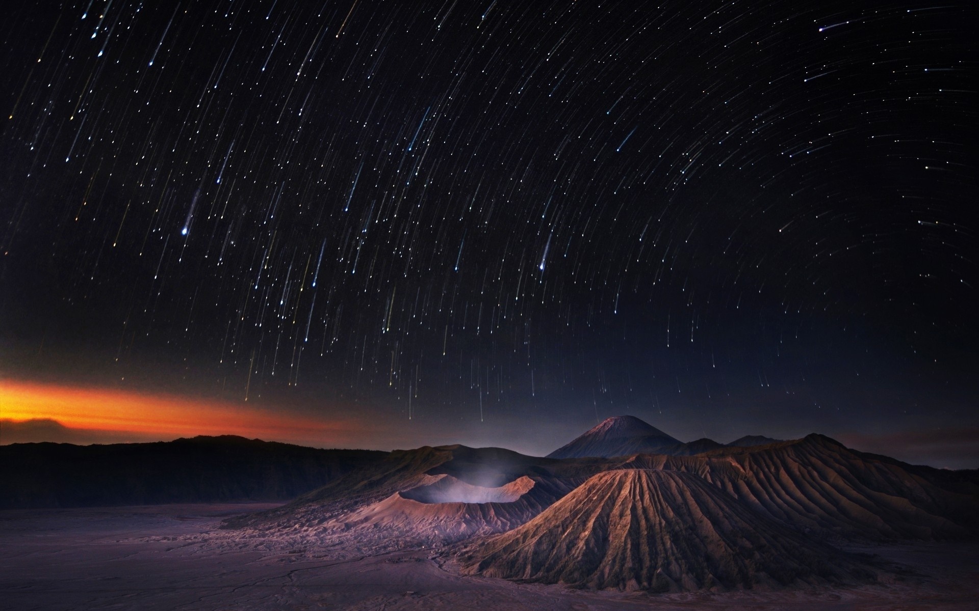 Volcanic landscape under a meteor shower at night HD Wallpaper