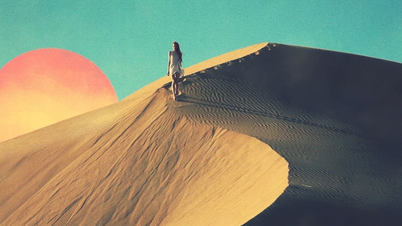 Woman walking on a sand dune with a large sun HD Wallpaper
