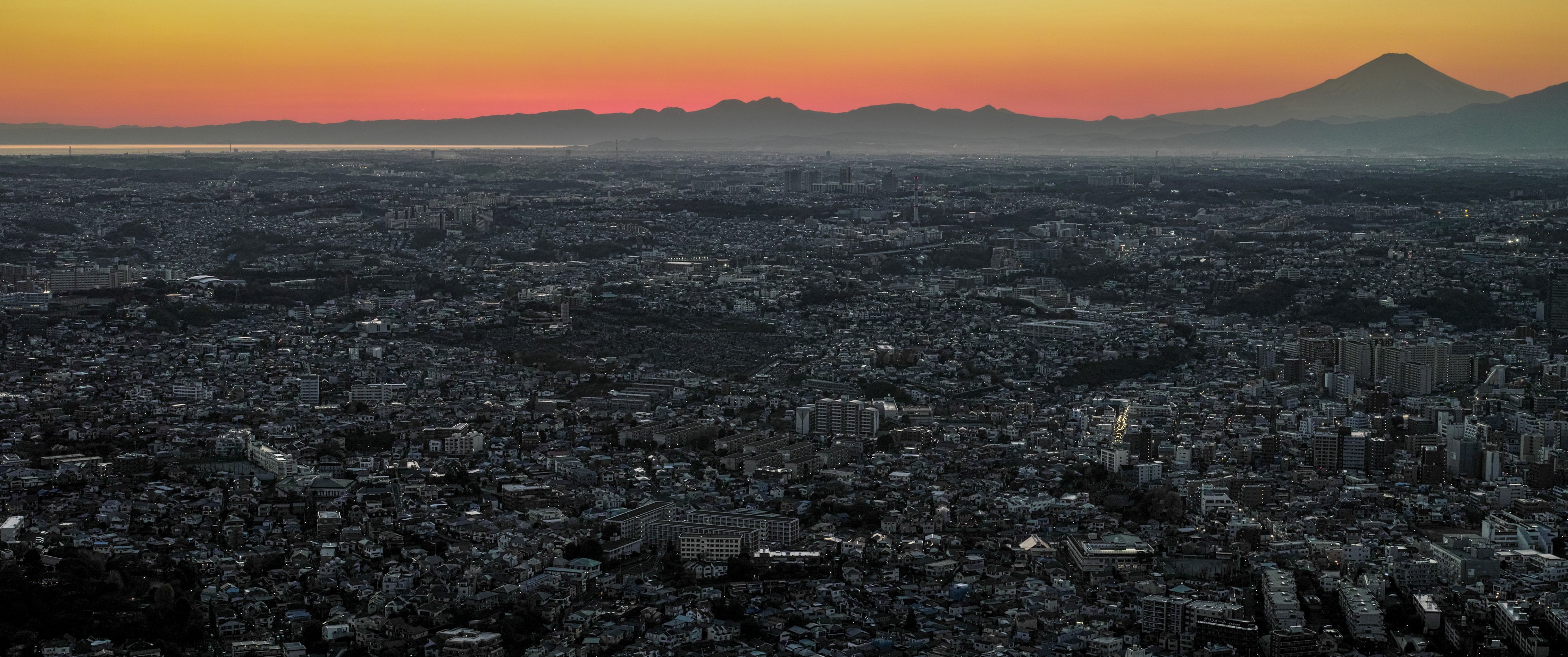 Cityscape at sunrise with mountains on the horizon HD Wallpaper