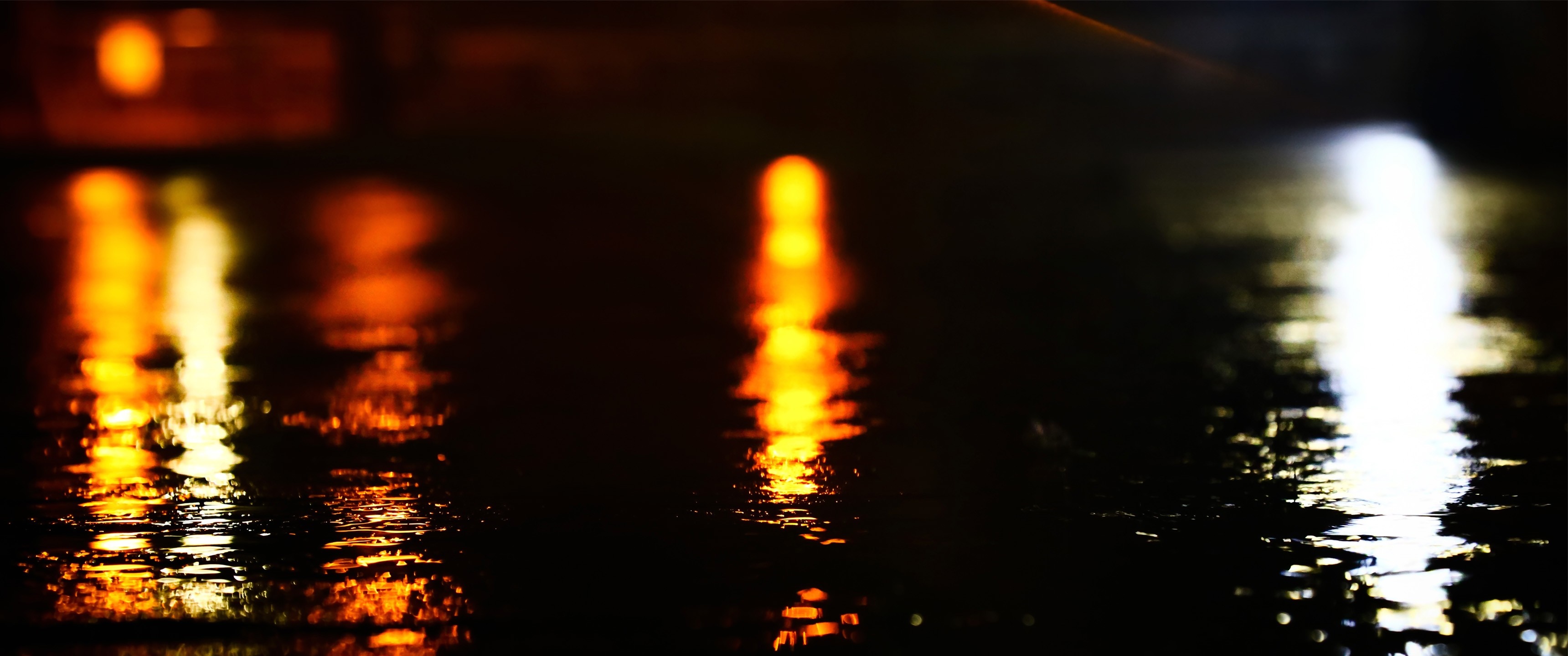 Nighttime reflections of lights on wet pavement HD Wallpaper