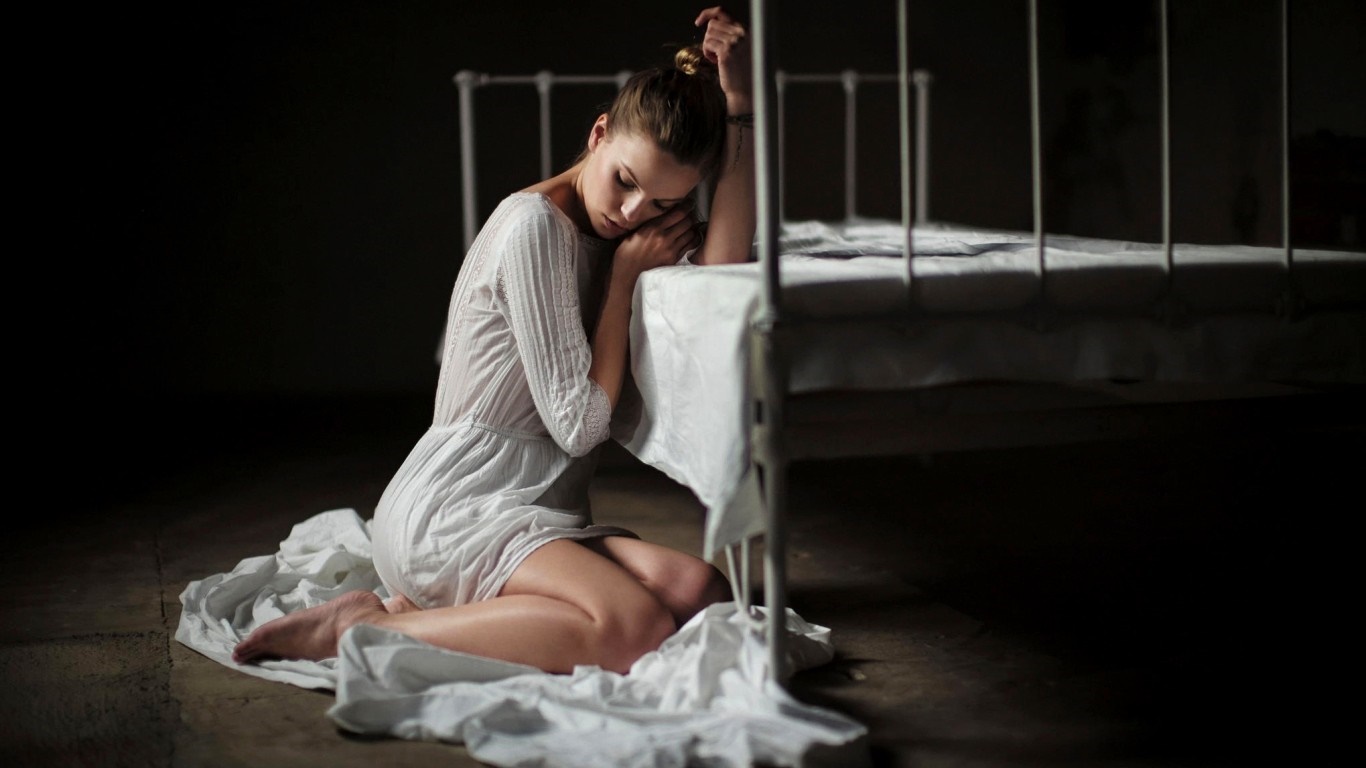 Woman in white dress sitting by a bed HD Wallpaper