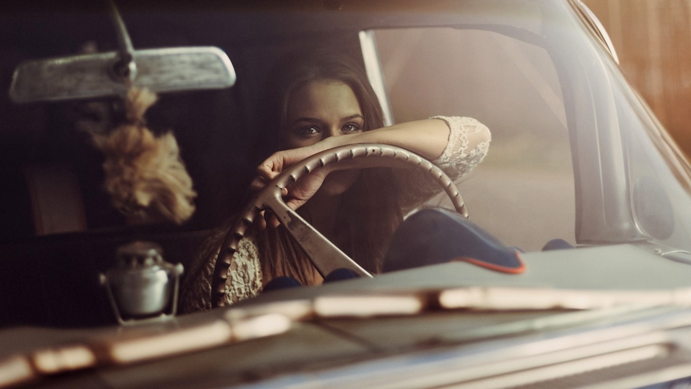 Woman in vintage car holding steering wheel HD Wallpaper