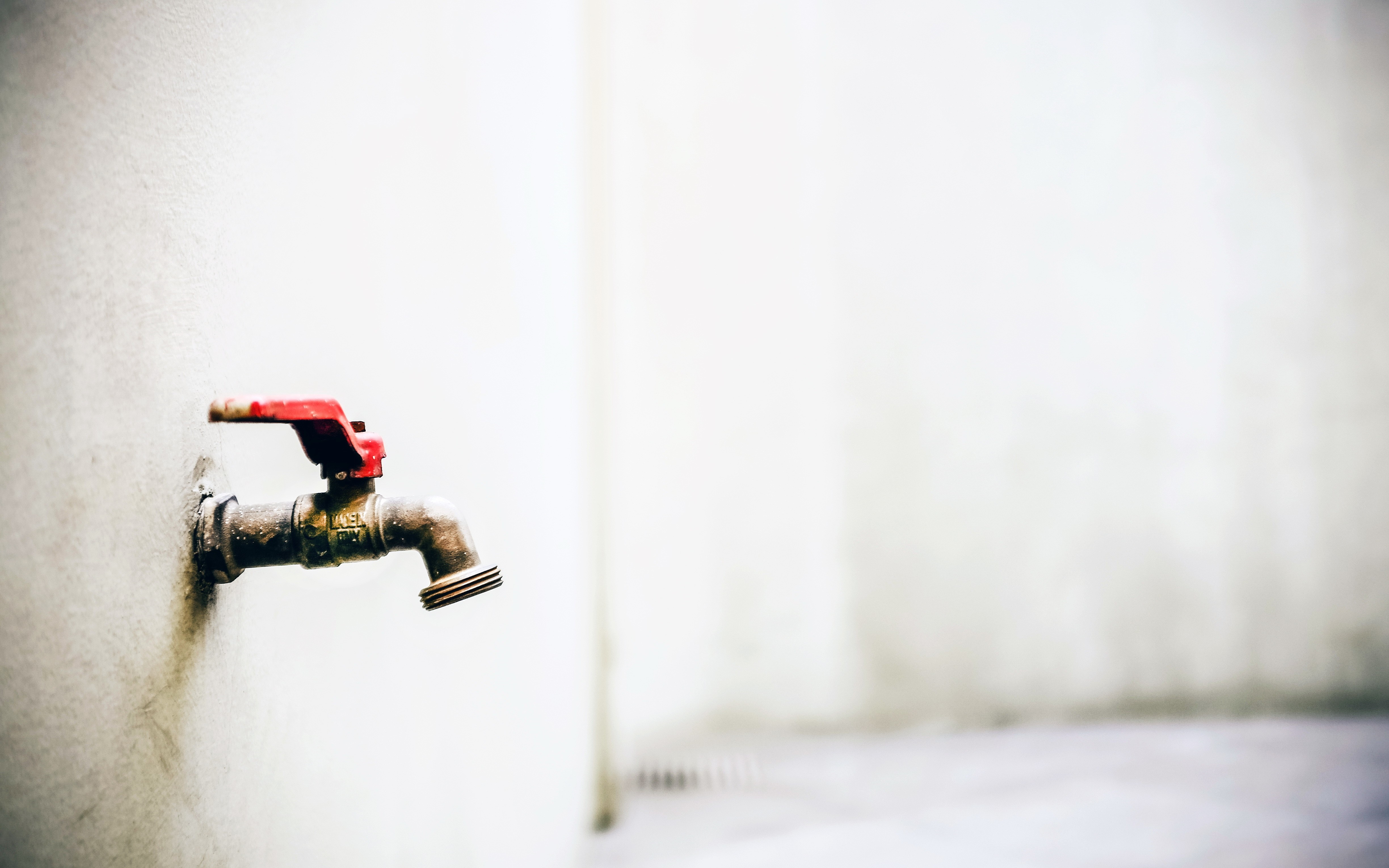 Red handled faucet on a white wall HD Wallpaper
