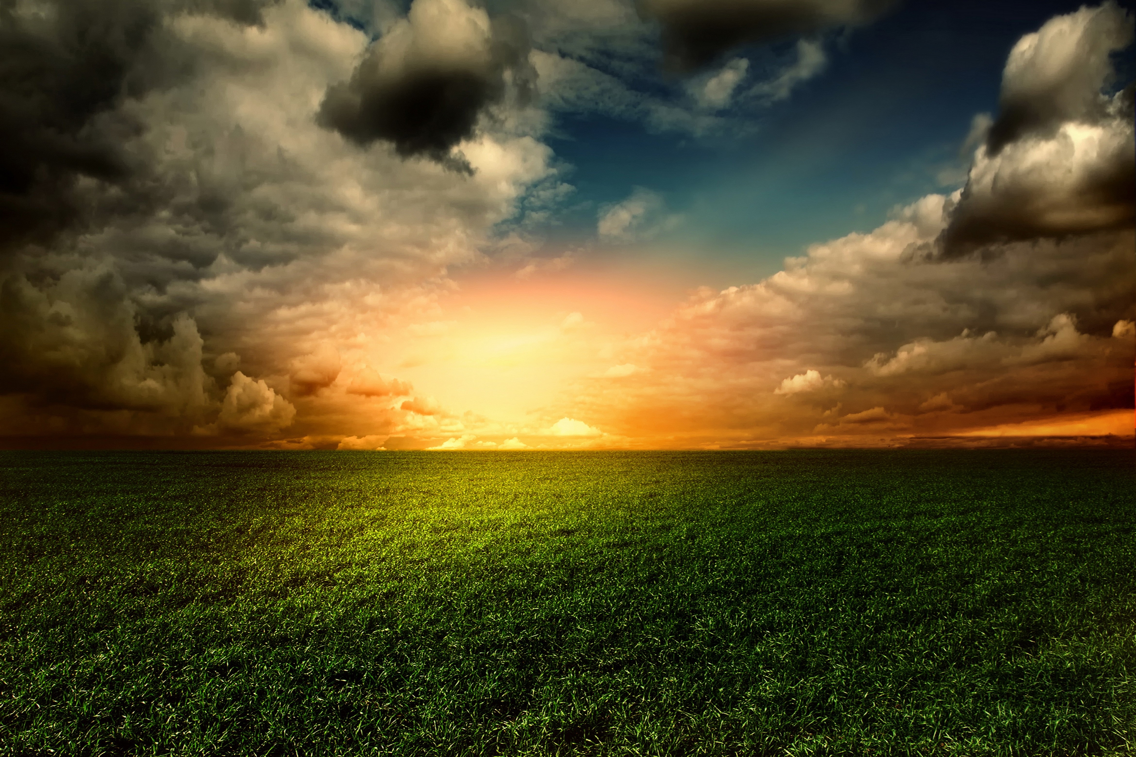 Sunset over a green field with dramatic clouds HD Wallpaper