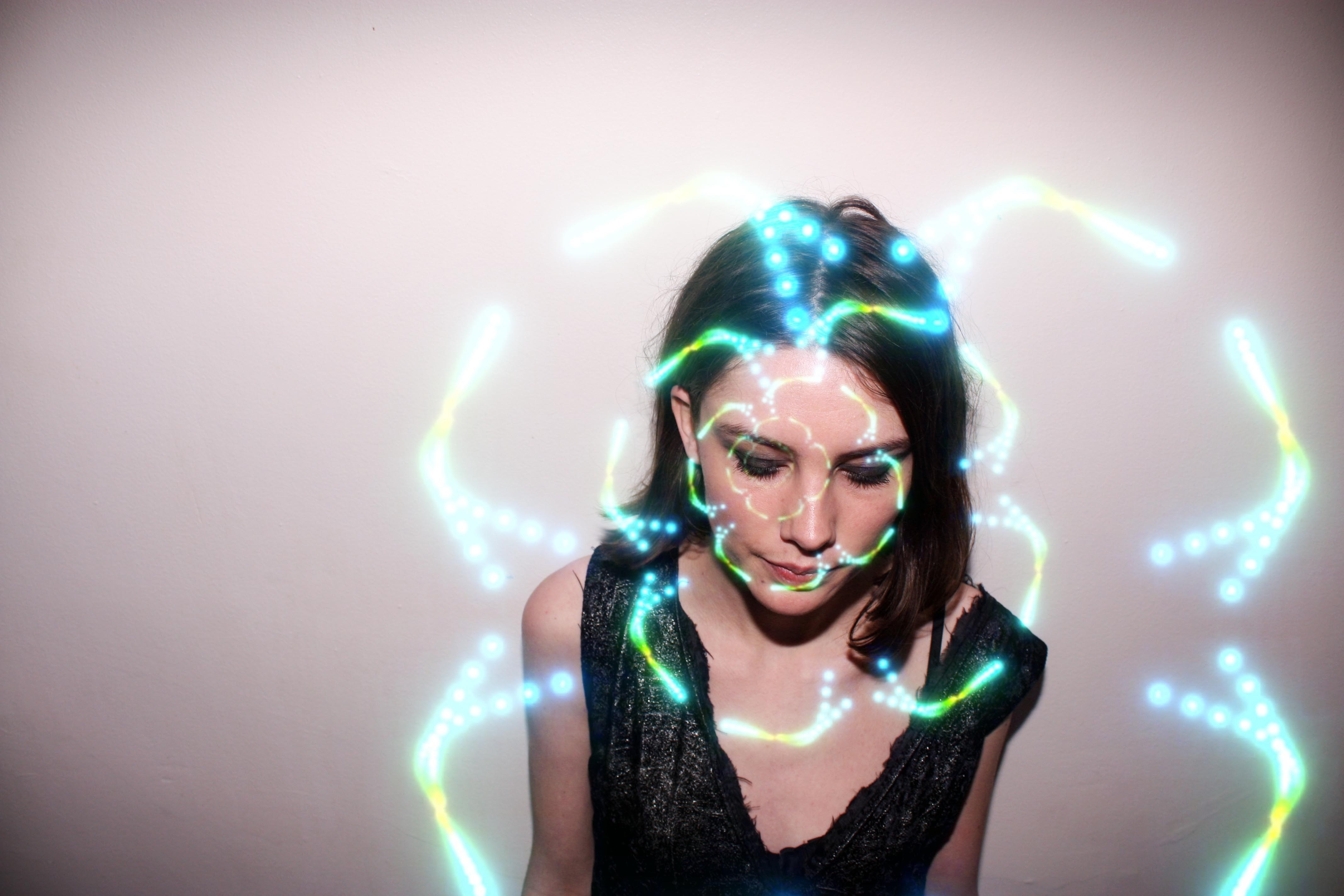 Woman with glowing blue and green lights on her face HD Wallpaper