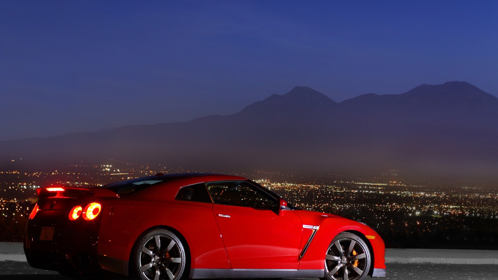 Red Nissan GT-R parked overlooking a city at night HD Wallpaper