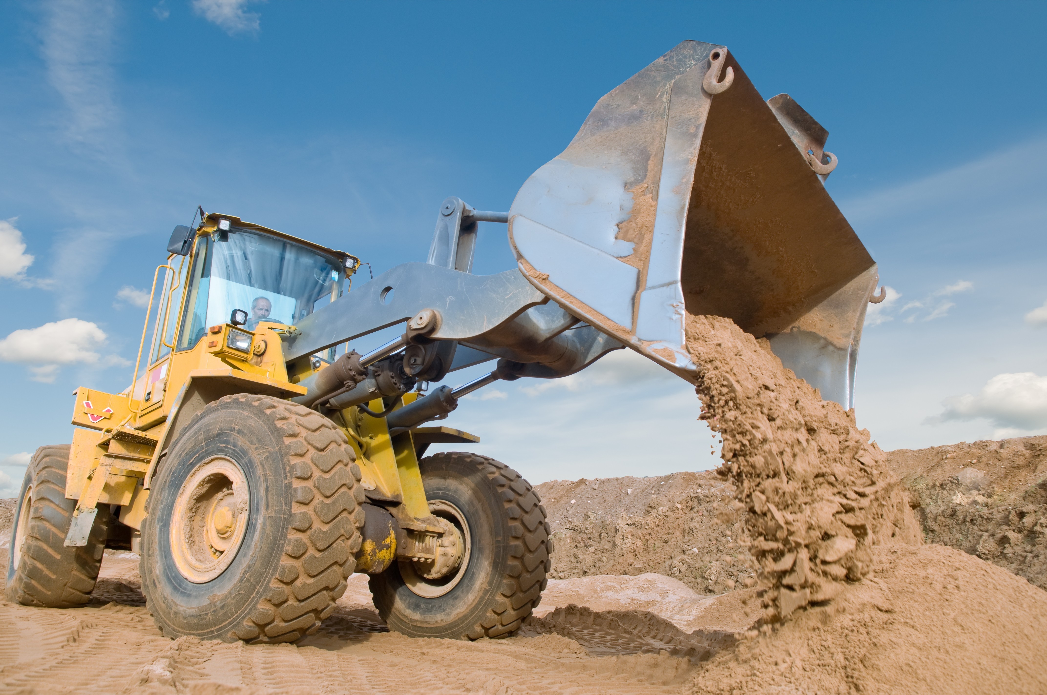 Yellow front loader dumping sand on a construction site HD Wallpaper