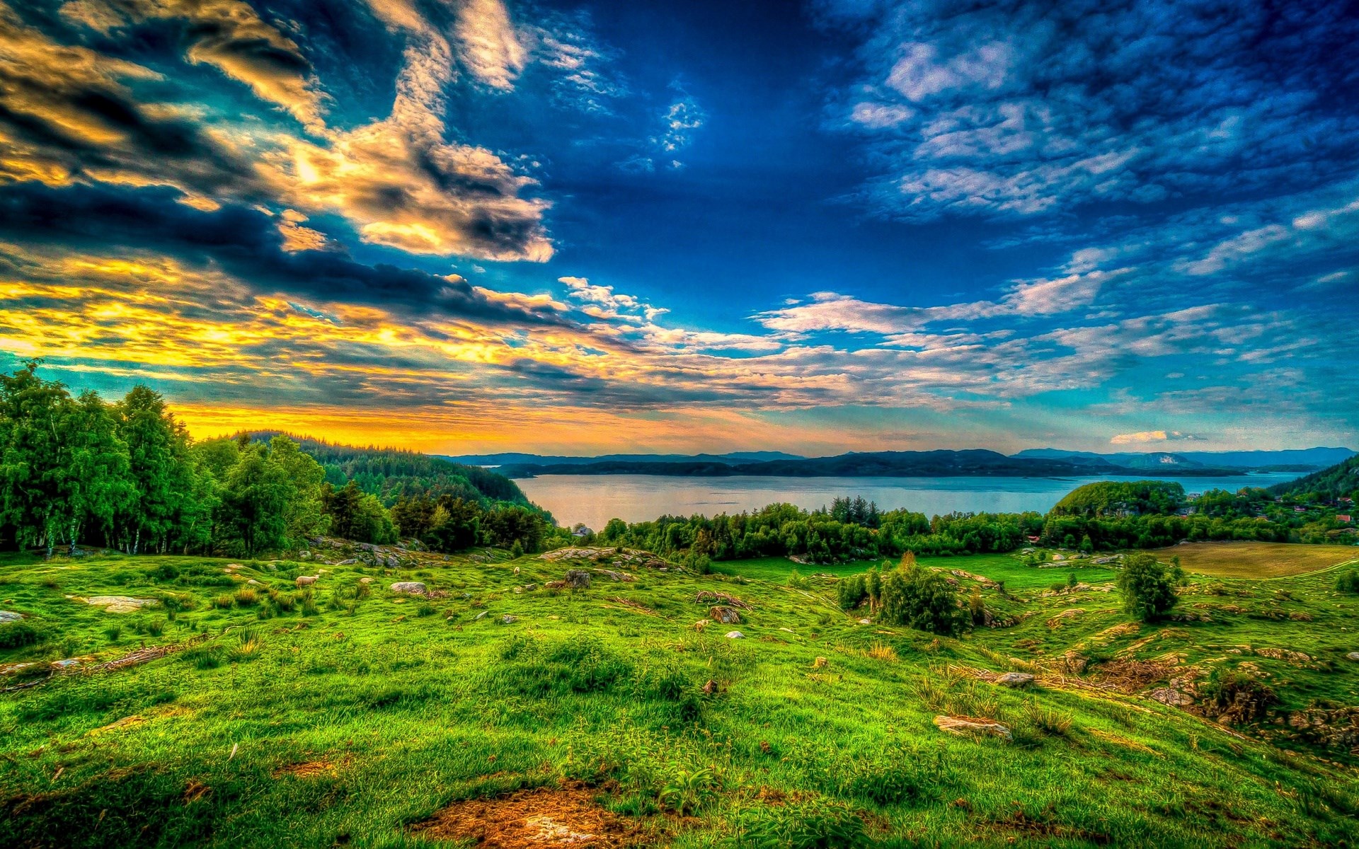 Green hills and a lake under a dramatic sky HD Wallpaper