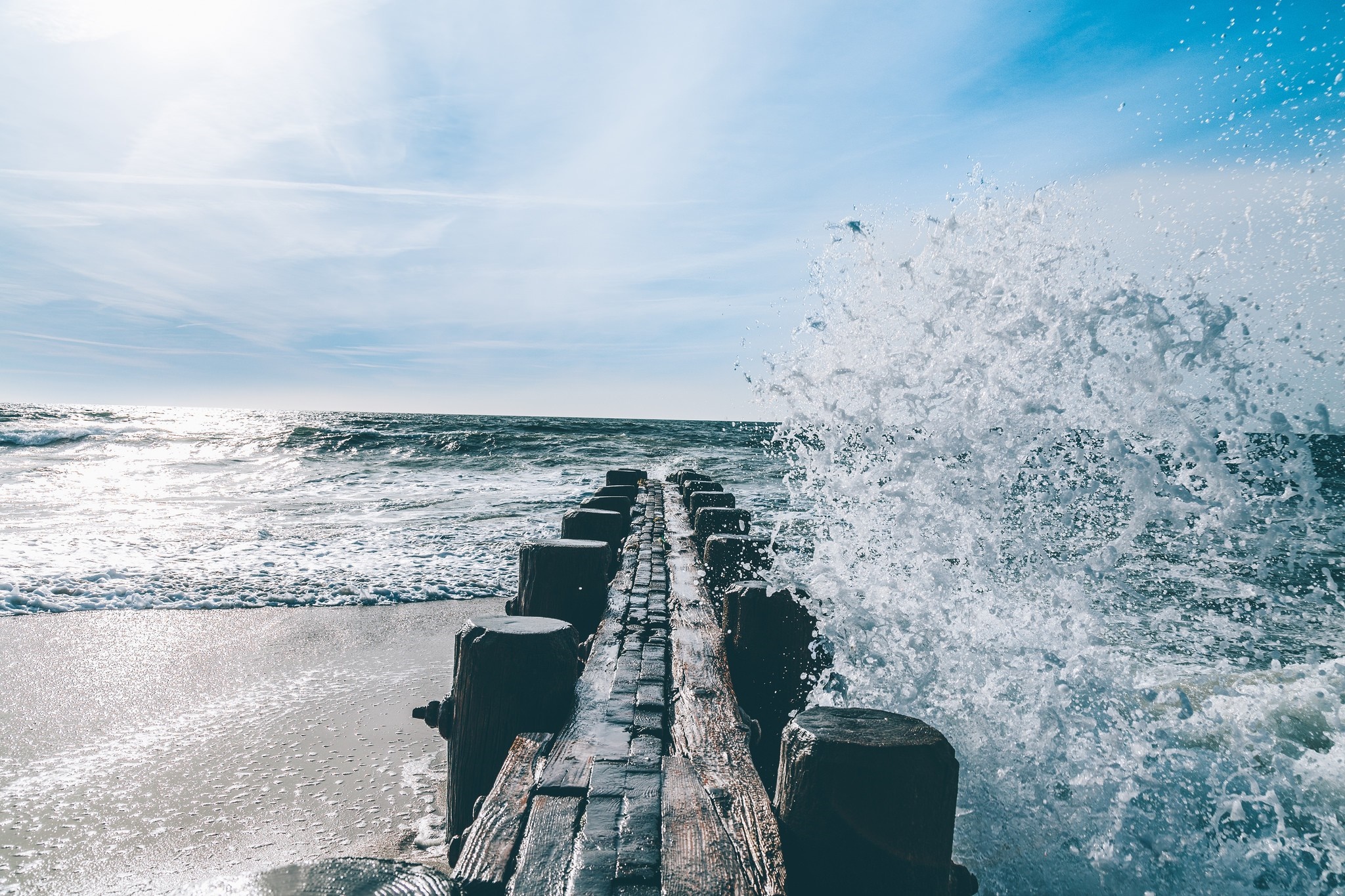 Waves crashing on a wooden pier at the sea HD Wallpaper