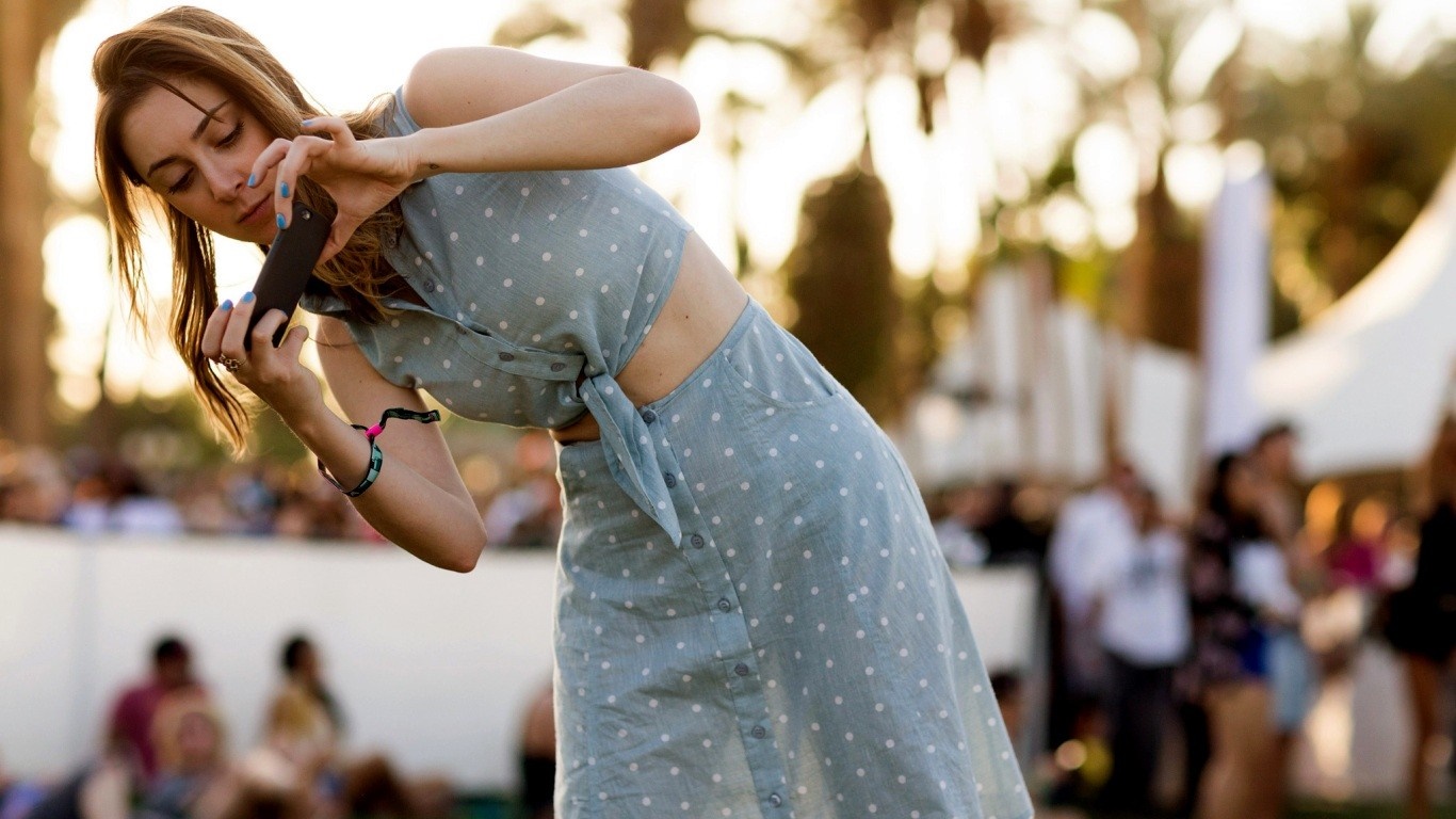 Woman in polka dot dress taking a photo with her phone HD Wallpaper