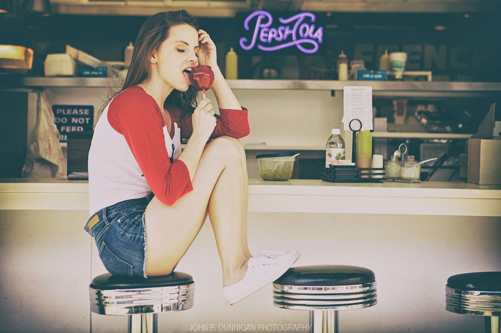 Woman eating a candy apple at a diner HD Wallpaper
