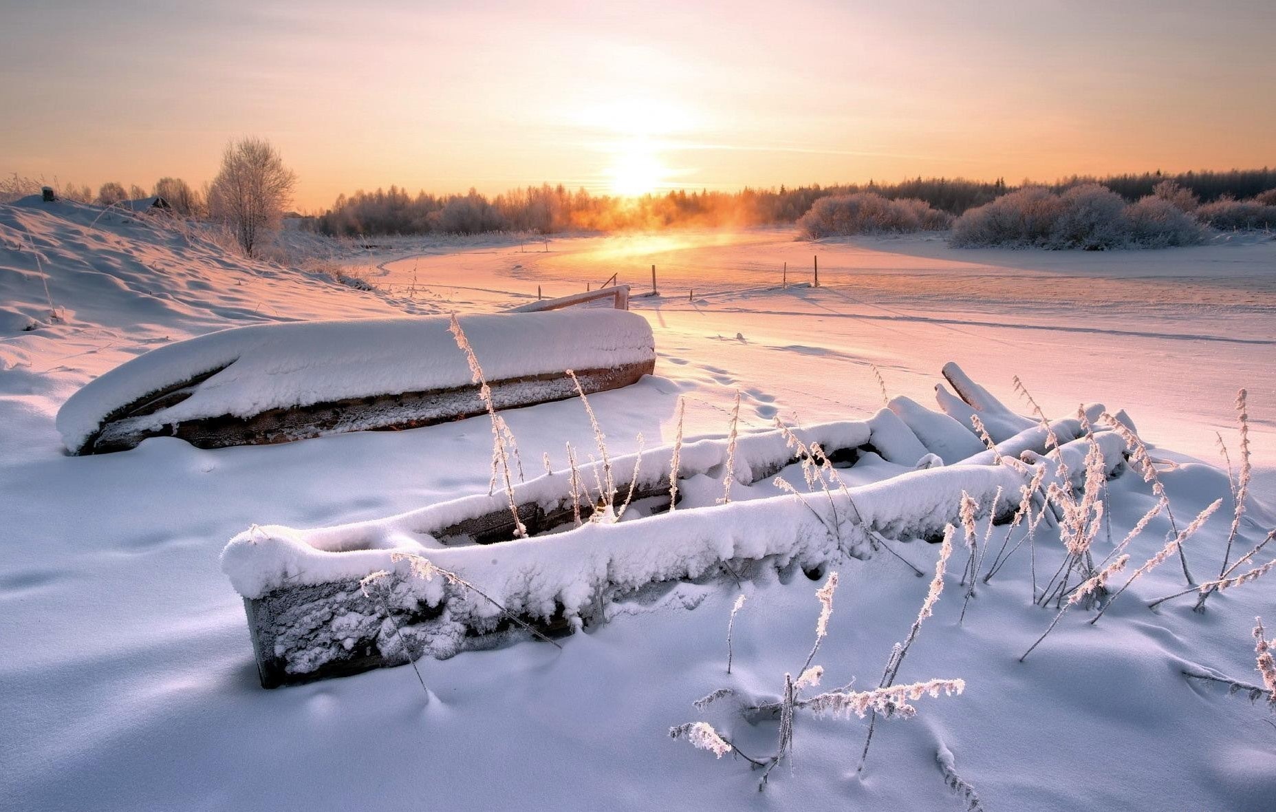Snow-covered boats on a frozen landscape at sunrise HD Wallpaper