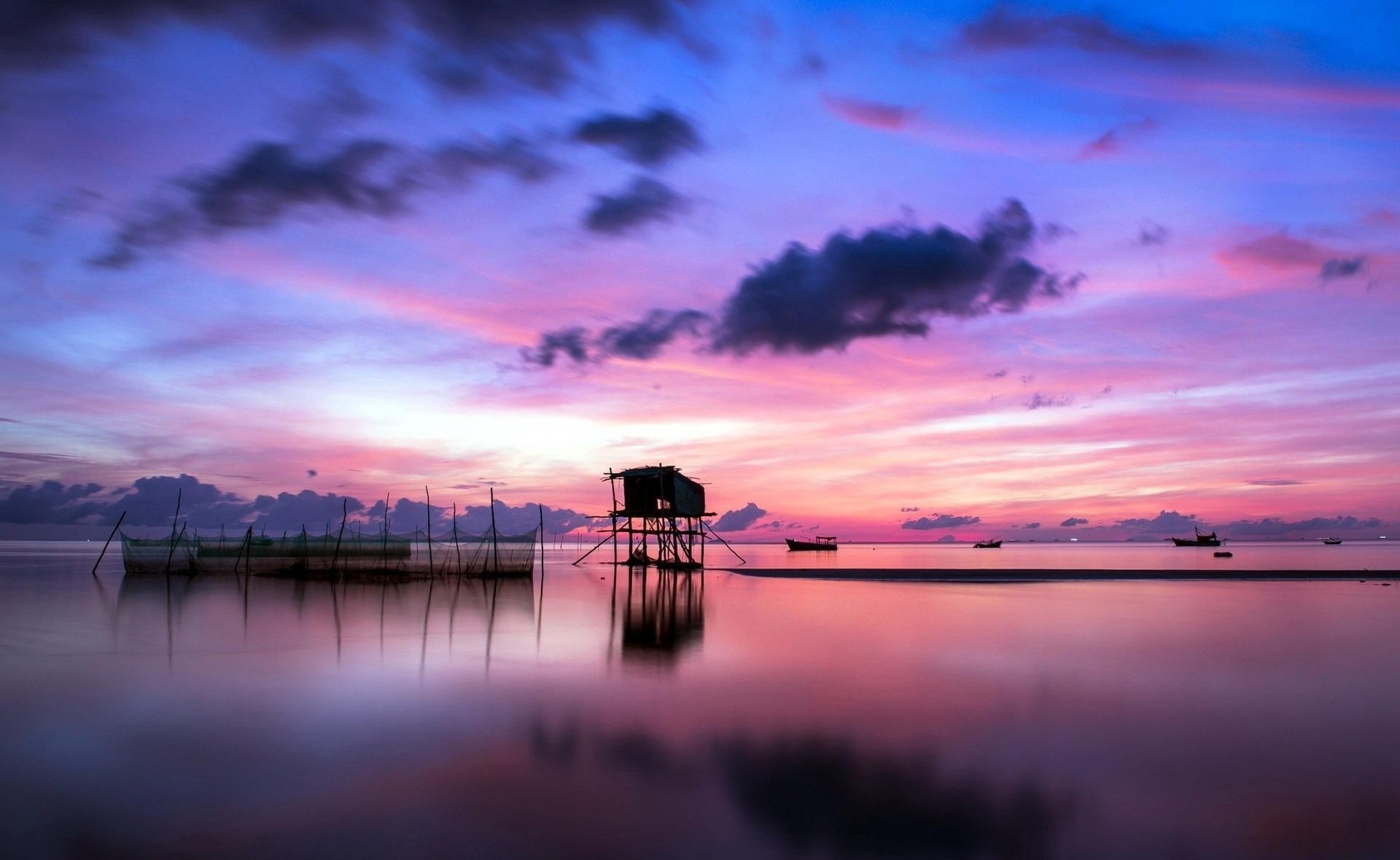 Sunset over the sea with a stilt house and fishing nets HD Wallpaper
