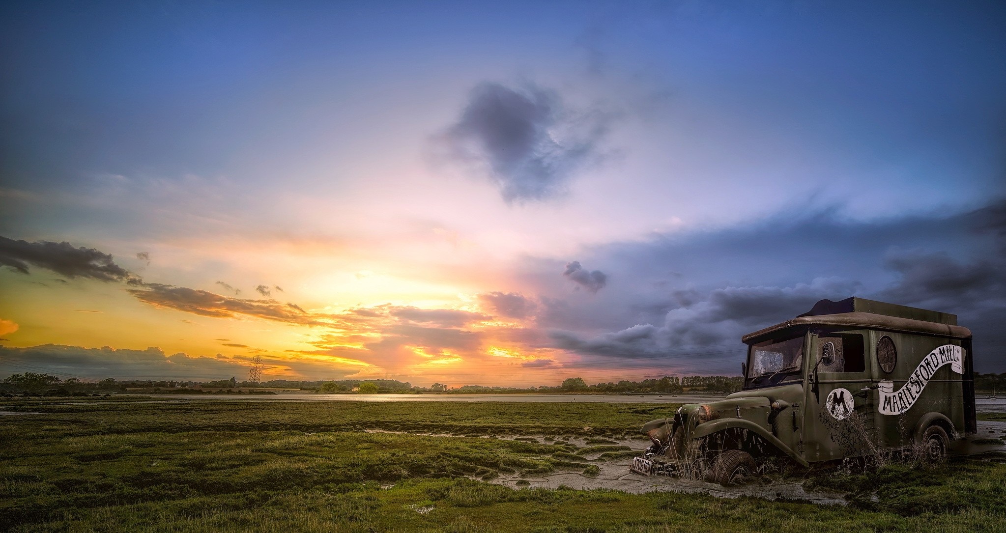 Abandoned vehicle in a marsh at sunset HD Wallpaper