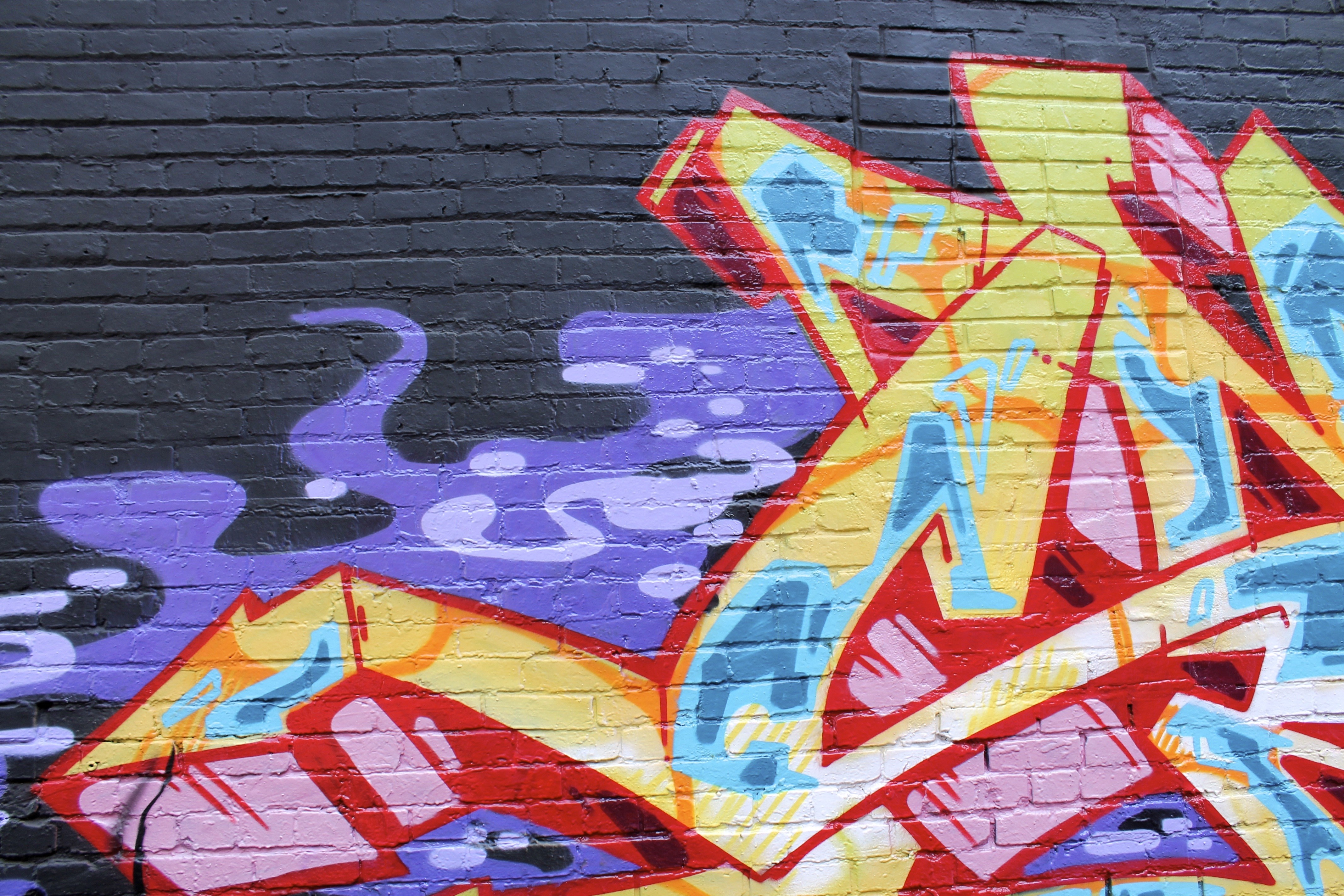 Graffiti mural with abstract shapes and colors on brick wall HD Wallpaper