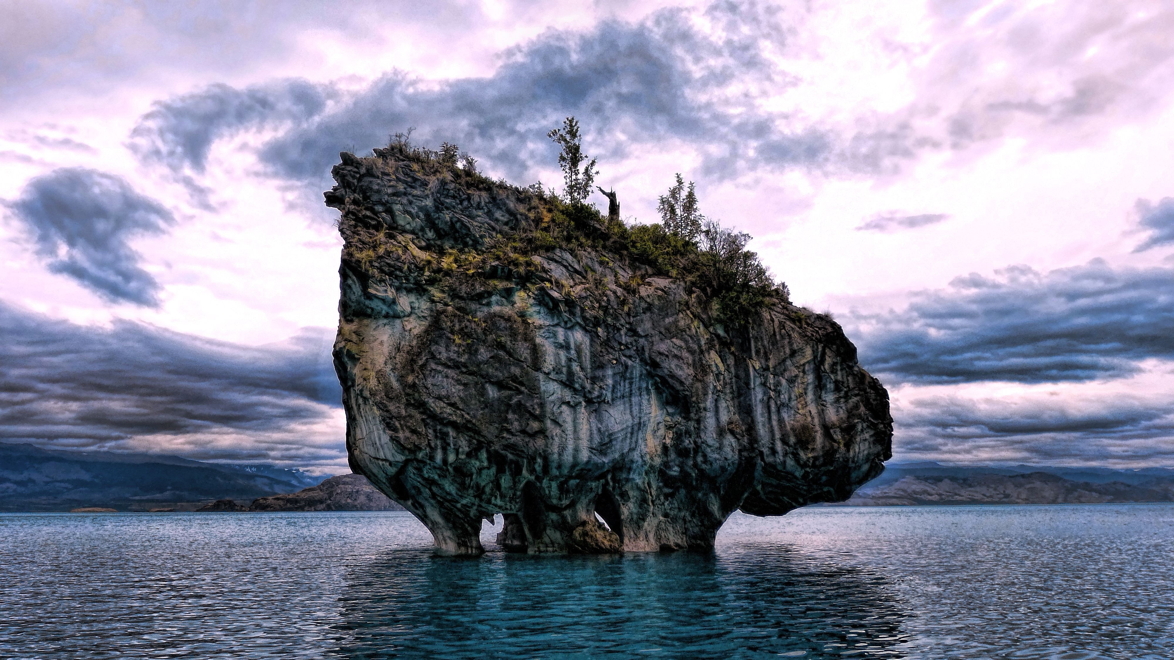 Rock formation in a lake with dramatic clouds HD Wallpaper
