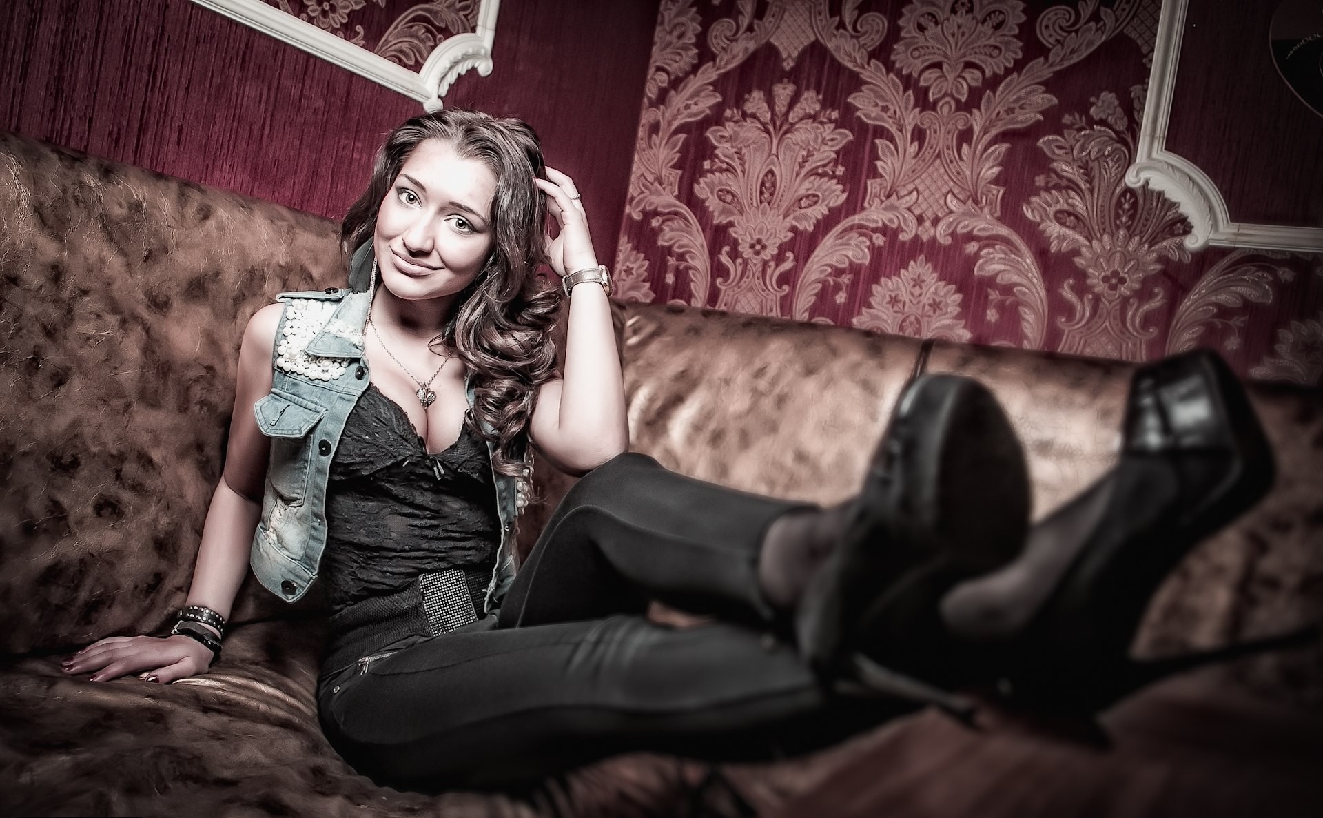 Woman in denim vest and black top sitting on a couch HD Wallpaper