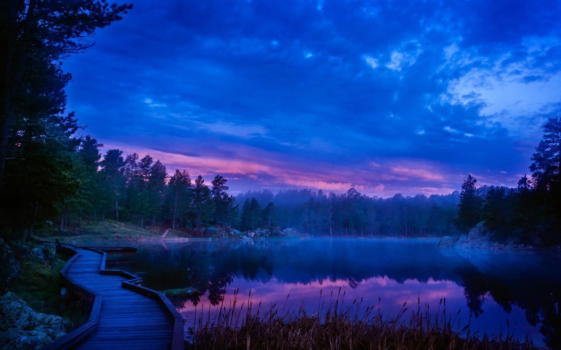 Wooden boardwalk by a misty lake at dusk HD Wallpaper