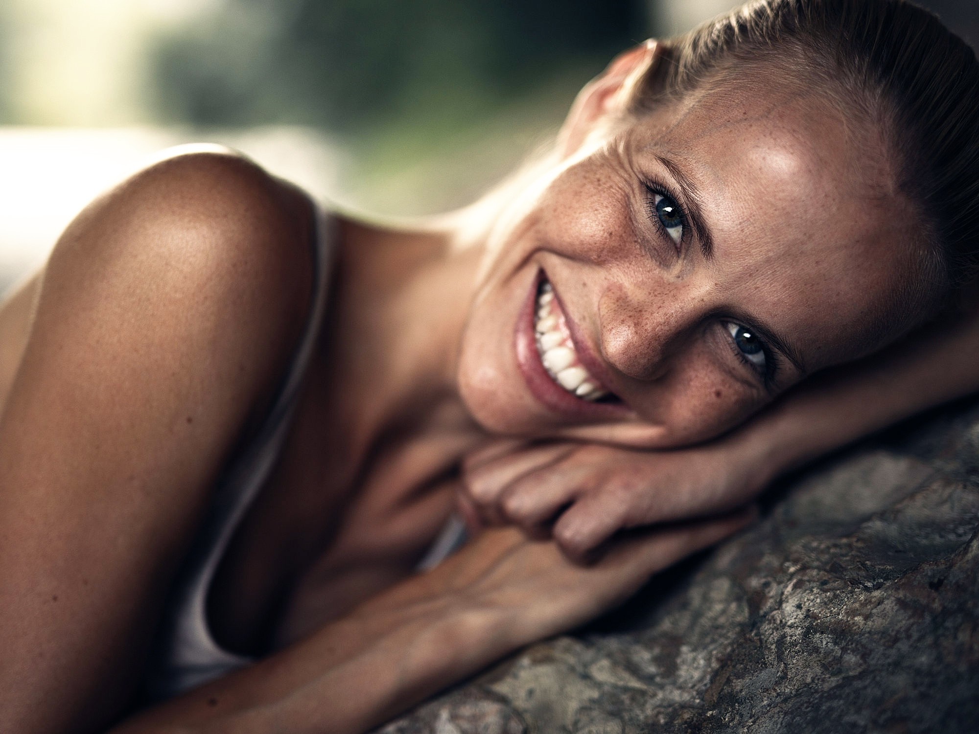 Woman with freckles smiling, resting head on hand HD Wallpaper