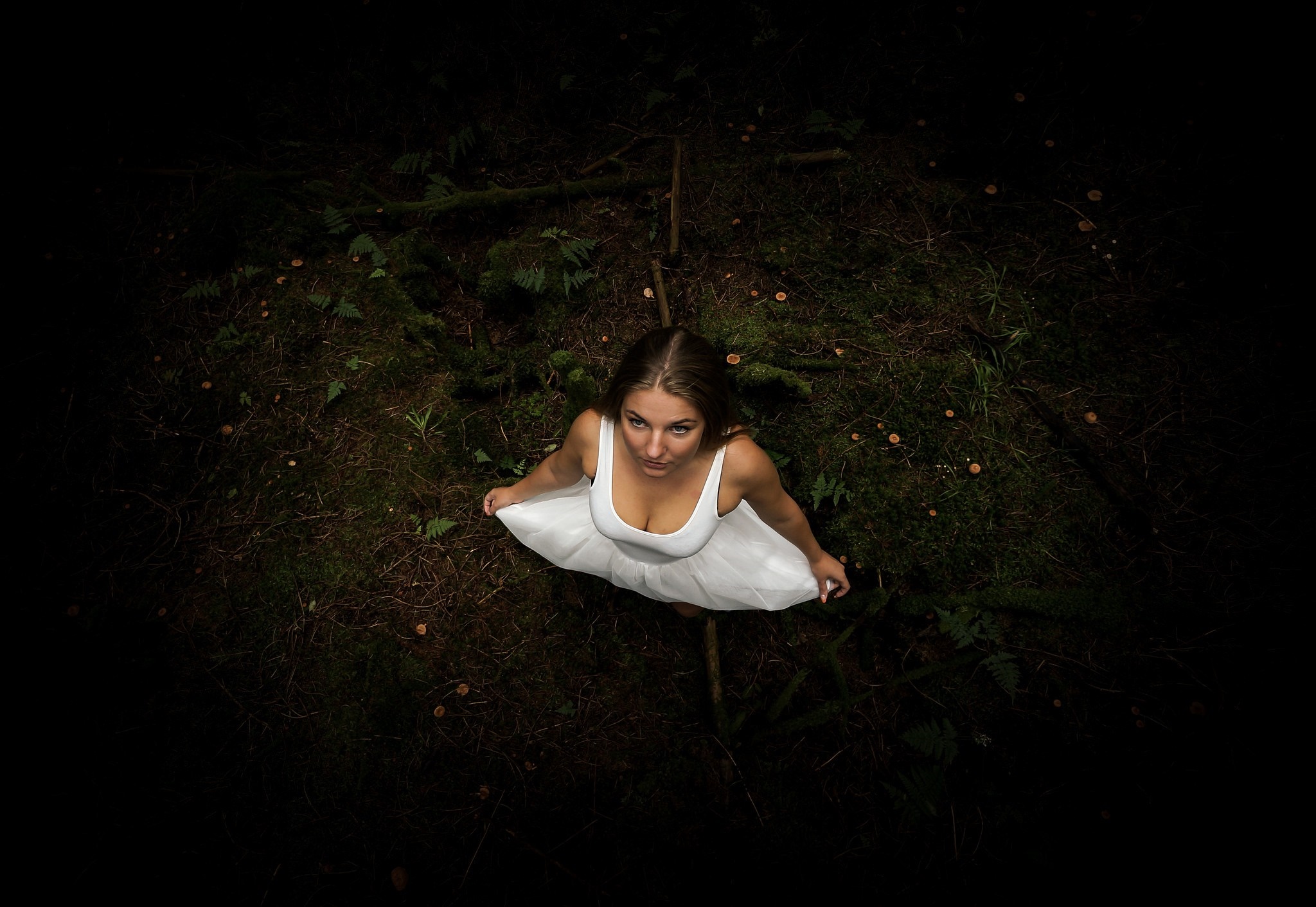 Woman in white dress looking up in dark forest HD Wallpaper