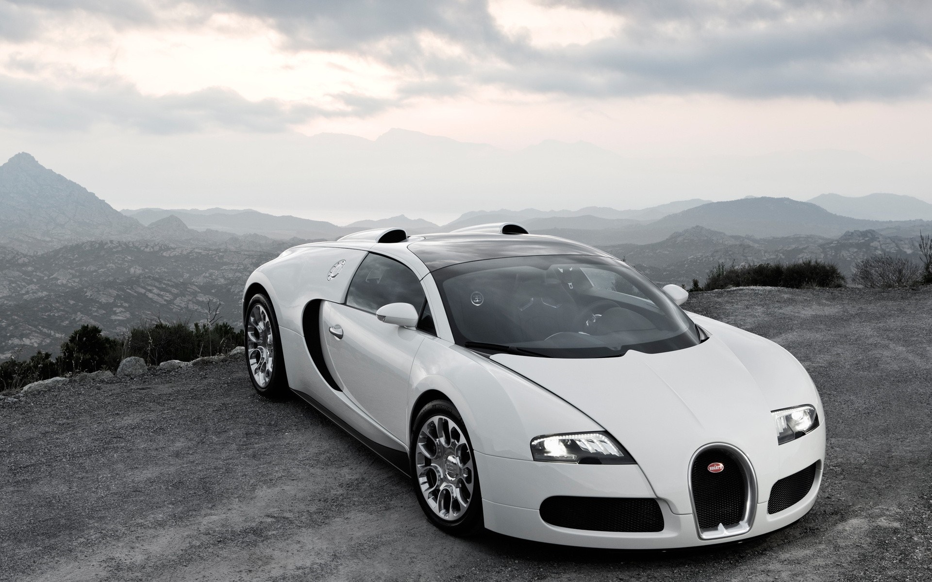 White Bugatti Veyron parked on a gravel road with mountains in the background HD Wallpaper