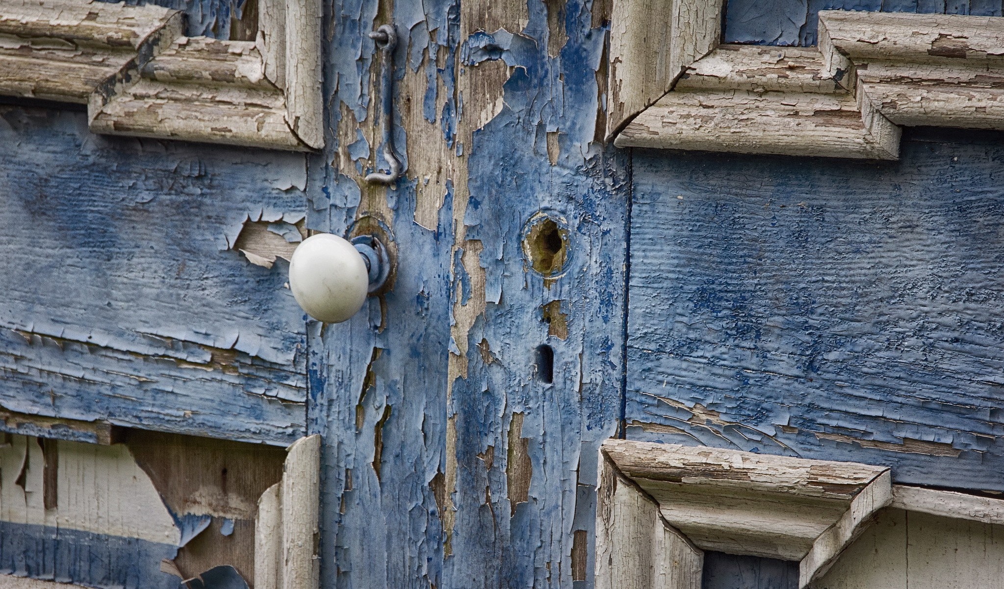 Peeling blue paint on an old wooden door with a doorknob HD Wallpaper