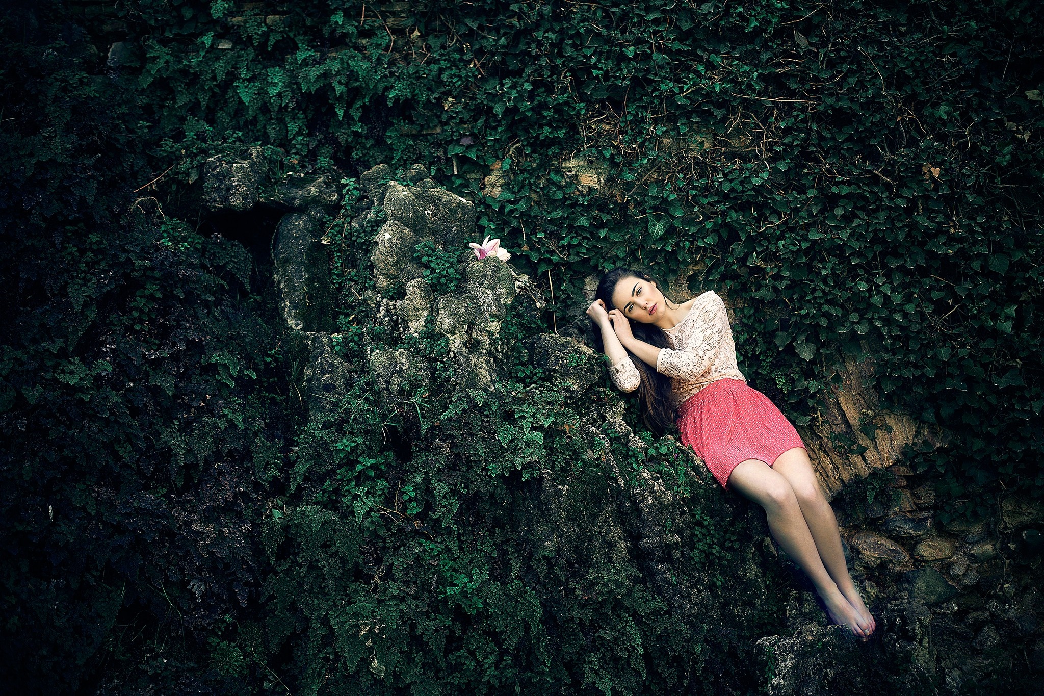 Woman lying on mossy rocks with a flower HD Wallpaper