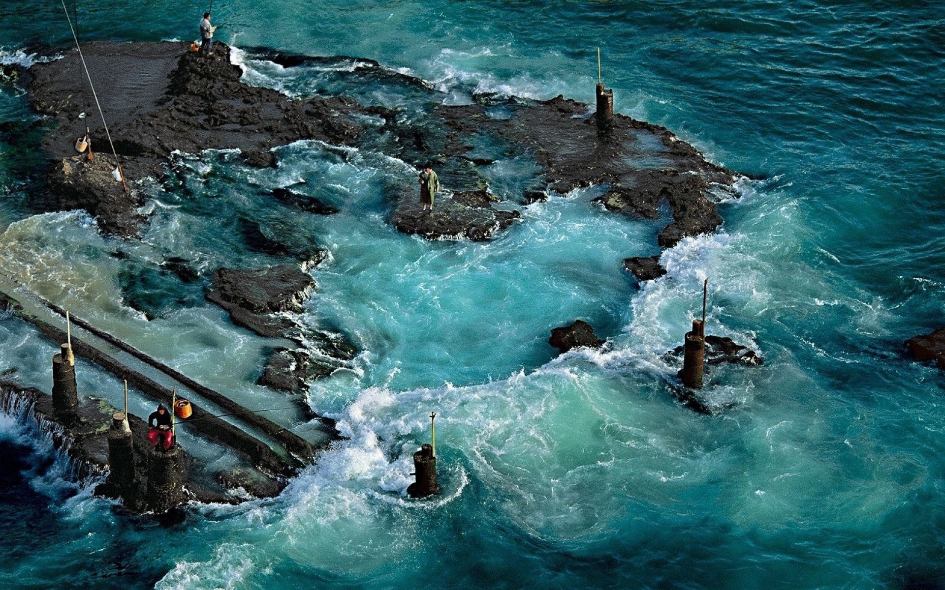 Fishermen on rocky coast with turquoise ocean waves HD Wallpaper