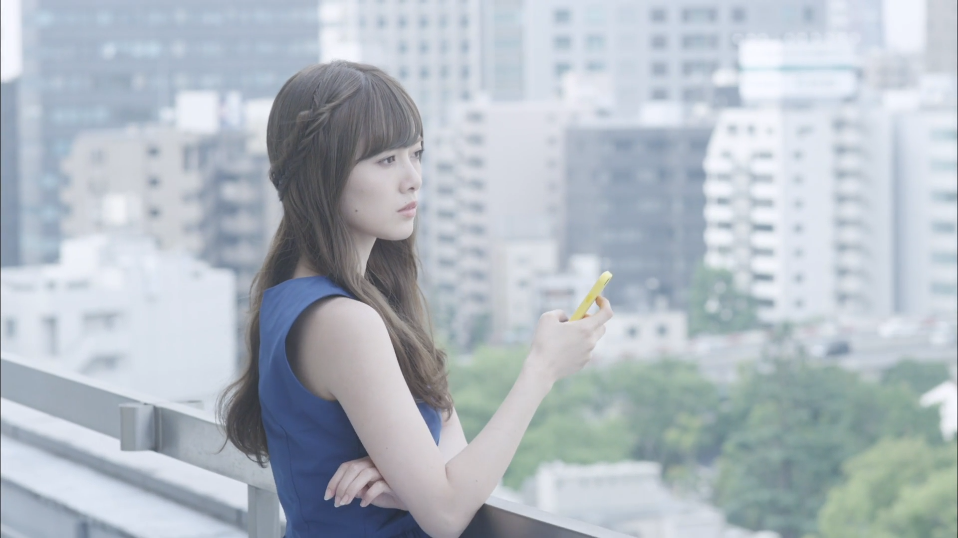 Contemplative Woman in Blue Dress Holding Smartphone HD Wallpaper