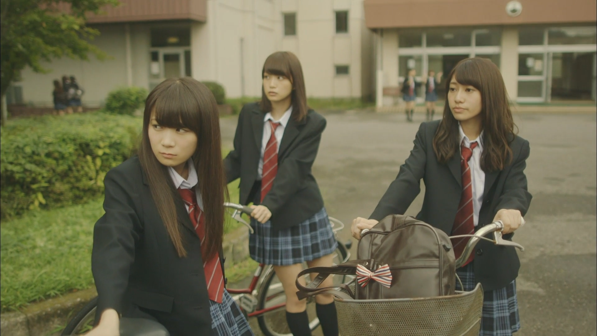 Three schoolgirls with bicycles outside a school HD Wallpaper