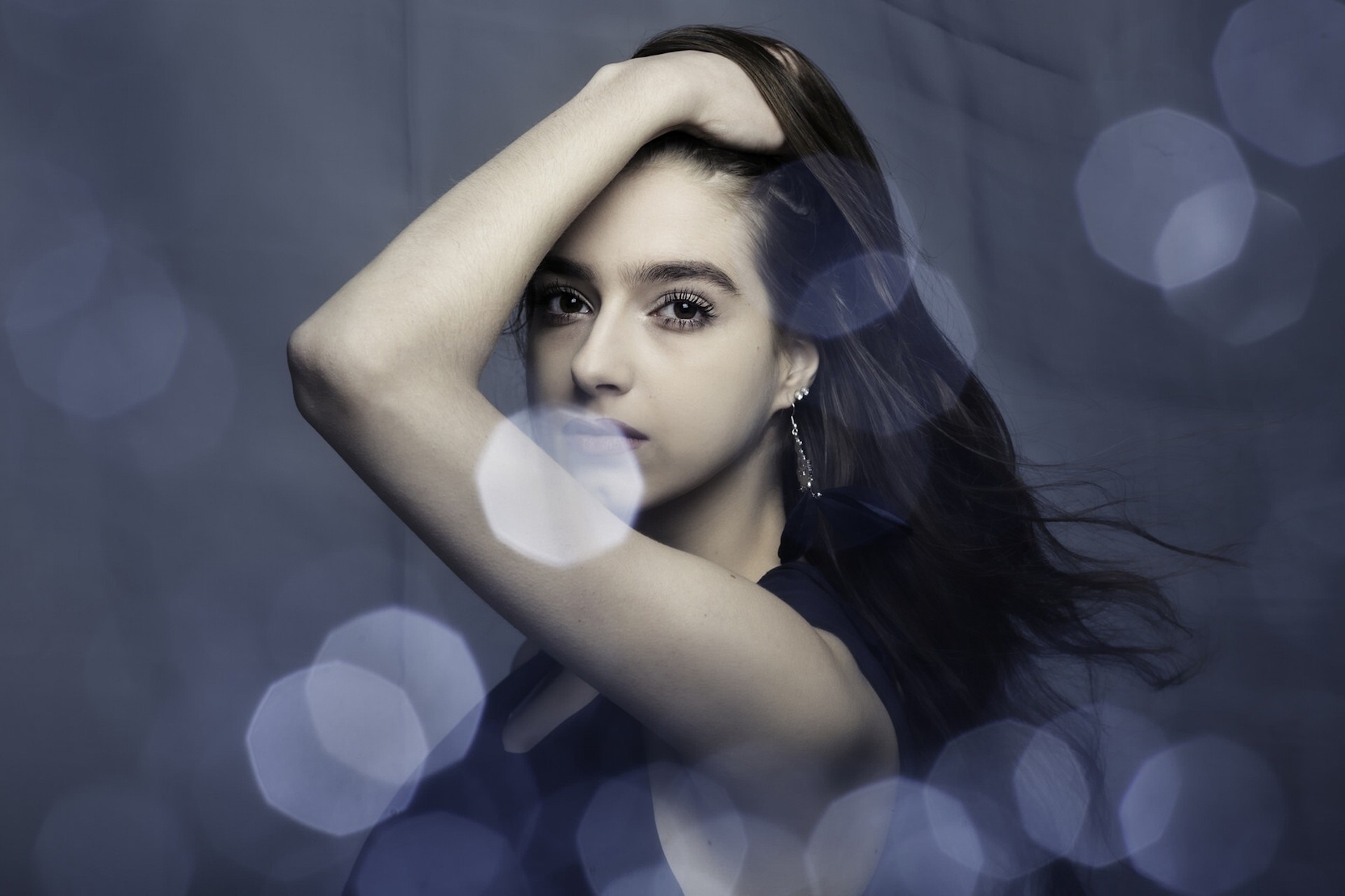 Woman with hand on head and blue bokeh HD Wallpaper