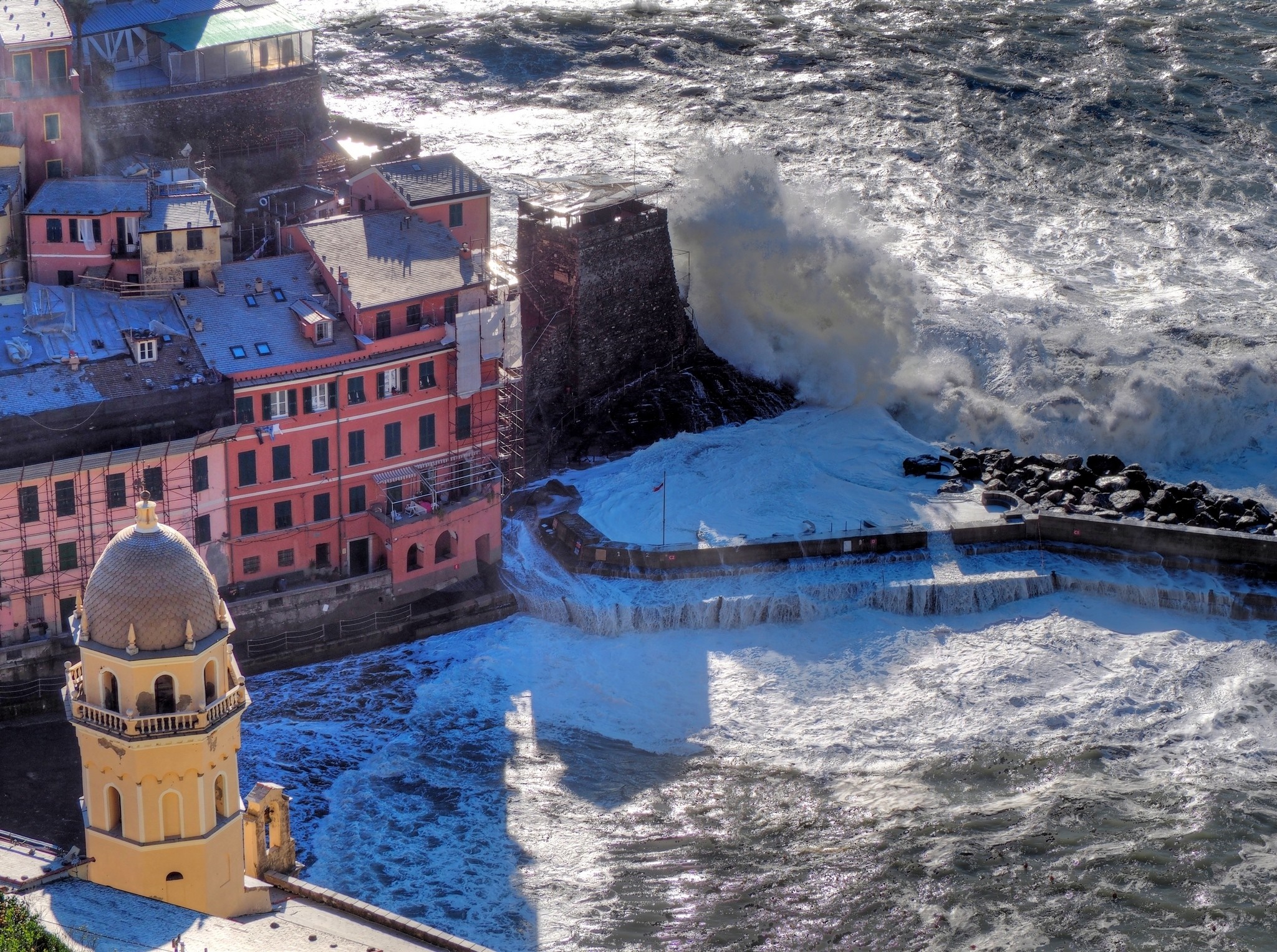 Vernazza, Italy coast with large waves crashing against buildings and a tower HD Wallpaper