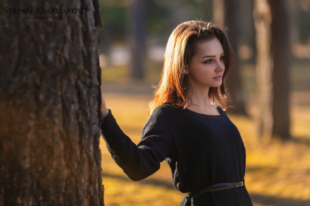 Woman leaning against a tree in autumn sunlight HD Wallpaper