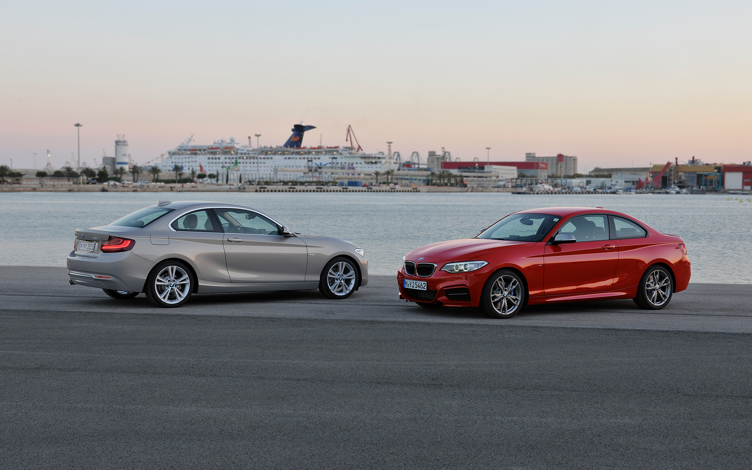 Two BMW coupes parked by a harbor with a cruise ship in the background HD Wallpaper