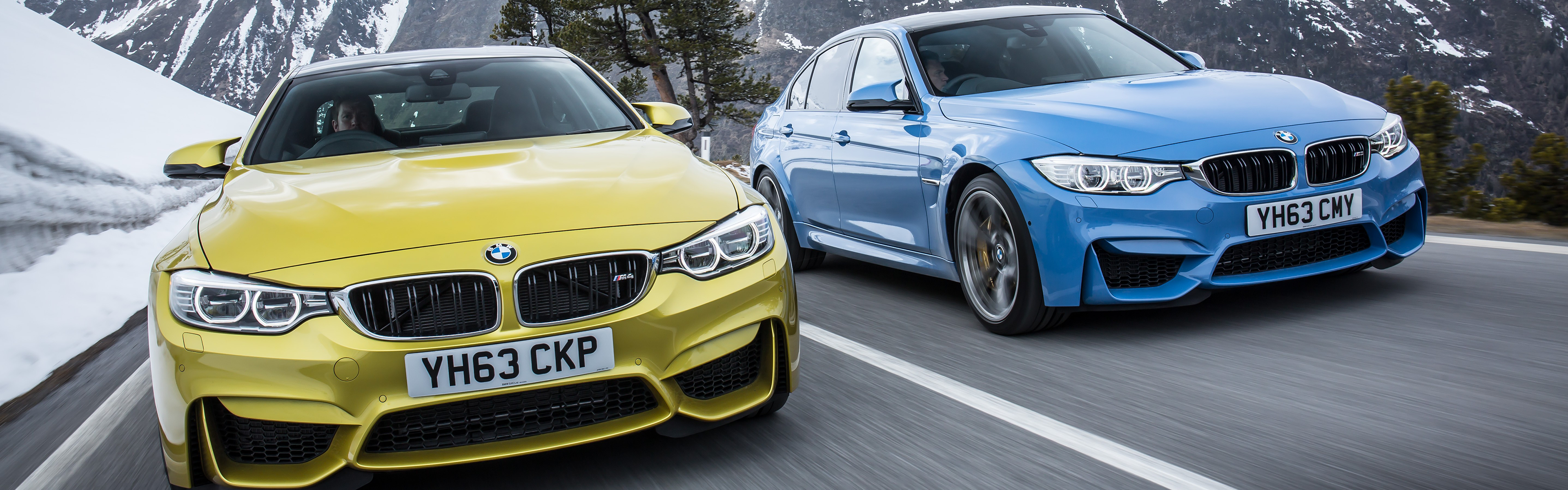 Two BMW M3 sedans driving on a mountain road HD Wallpaper