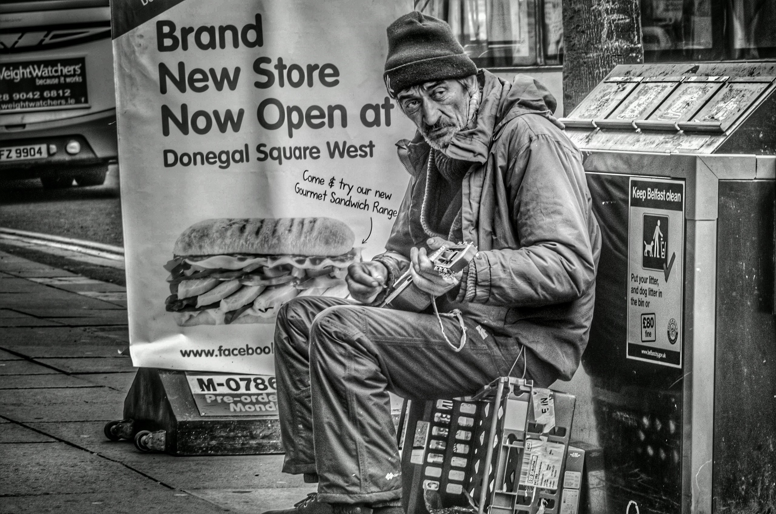 Man playing guitar in front of a store advertisement HD Wallpaper
