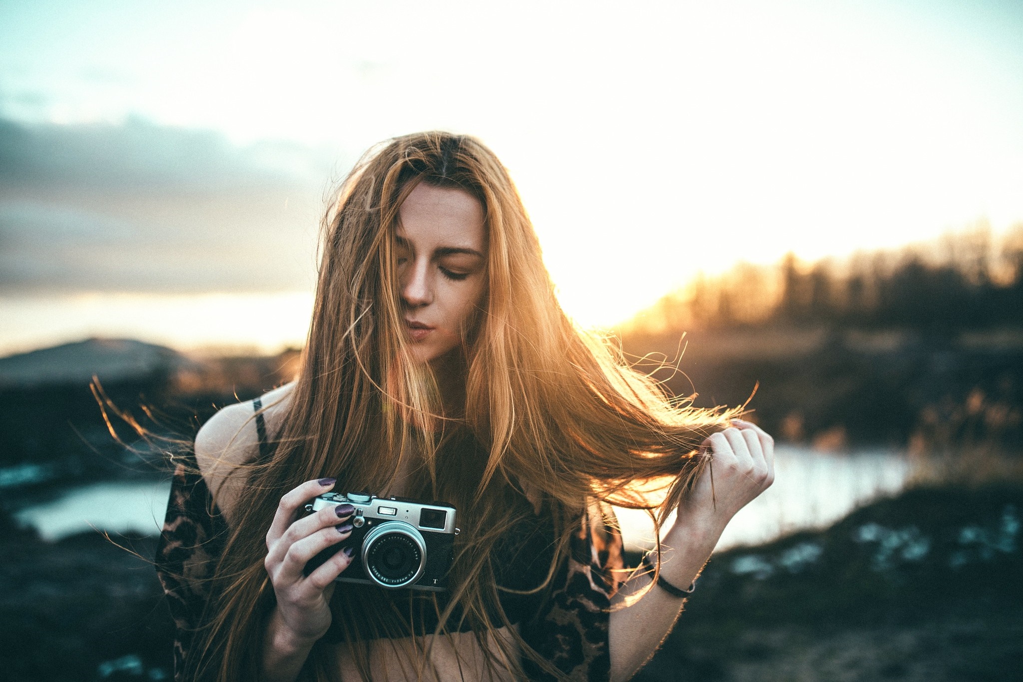 Woman holding a camera outdoors at sunset HD Wallpaper