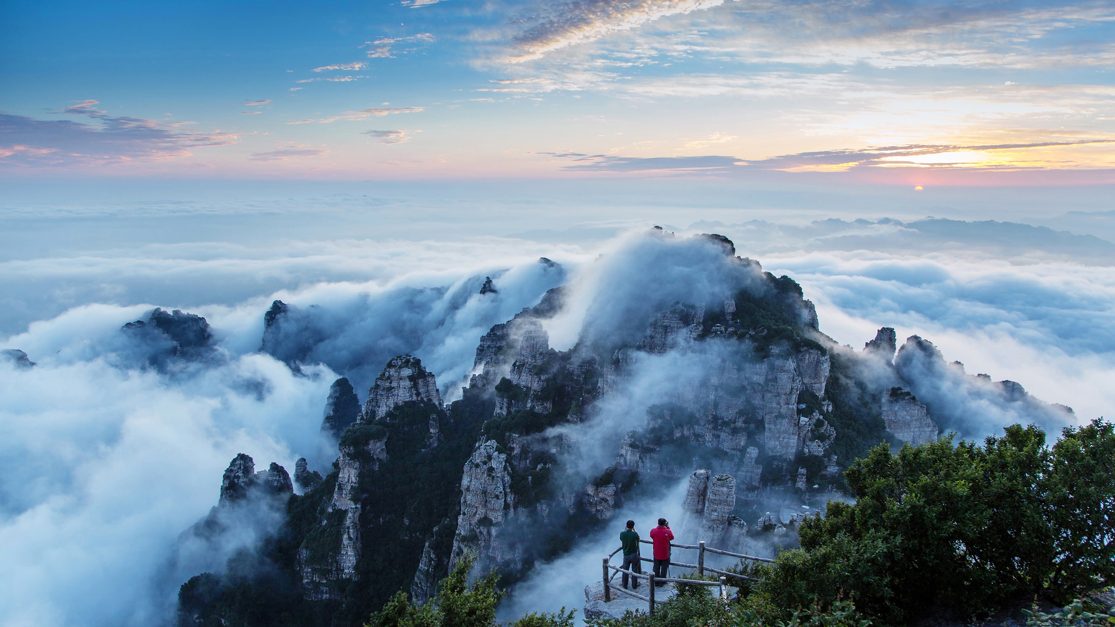 Mountain peaks shrouded in clouds at sunrise HD Wallpaper