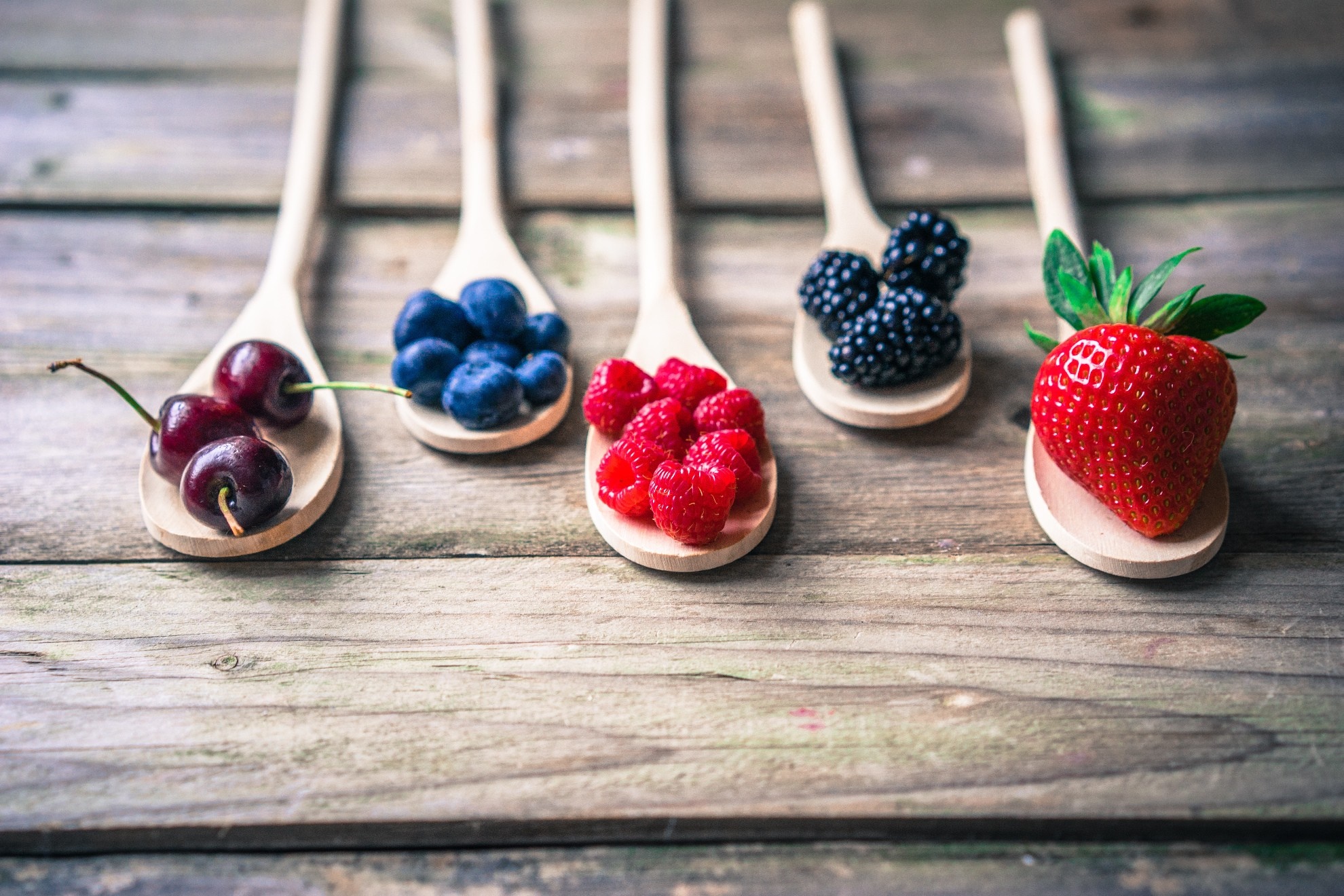 Wooden spoons filled with assorted berries and fruits HD Wallpaper