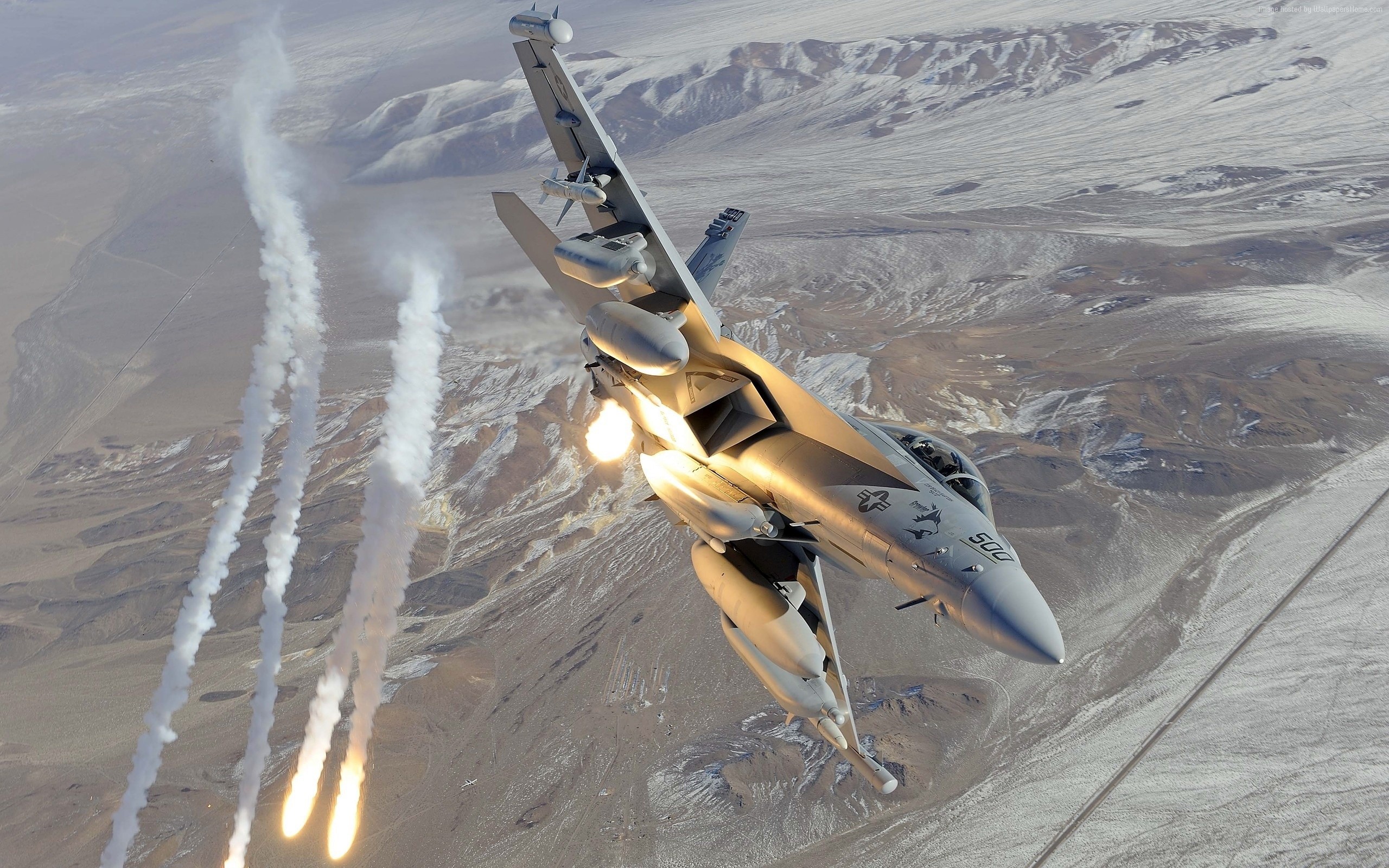 Boeing EA-18 Growler releasing flares over desert landscape HD Wallpaper