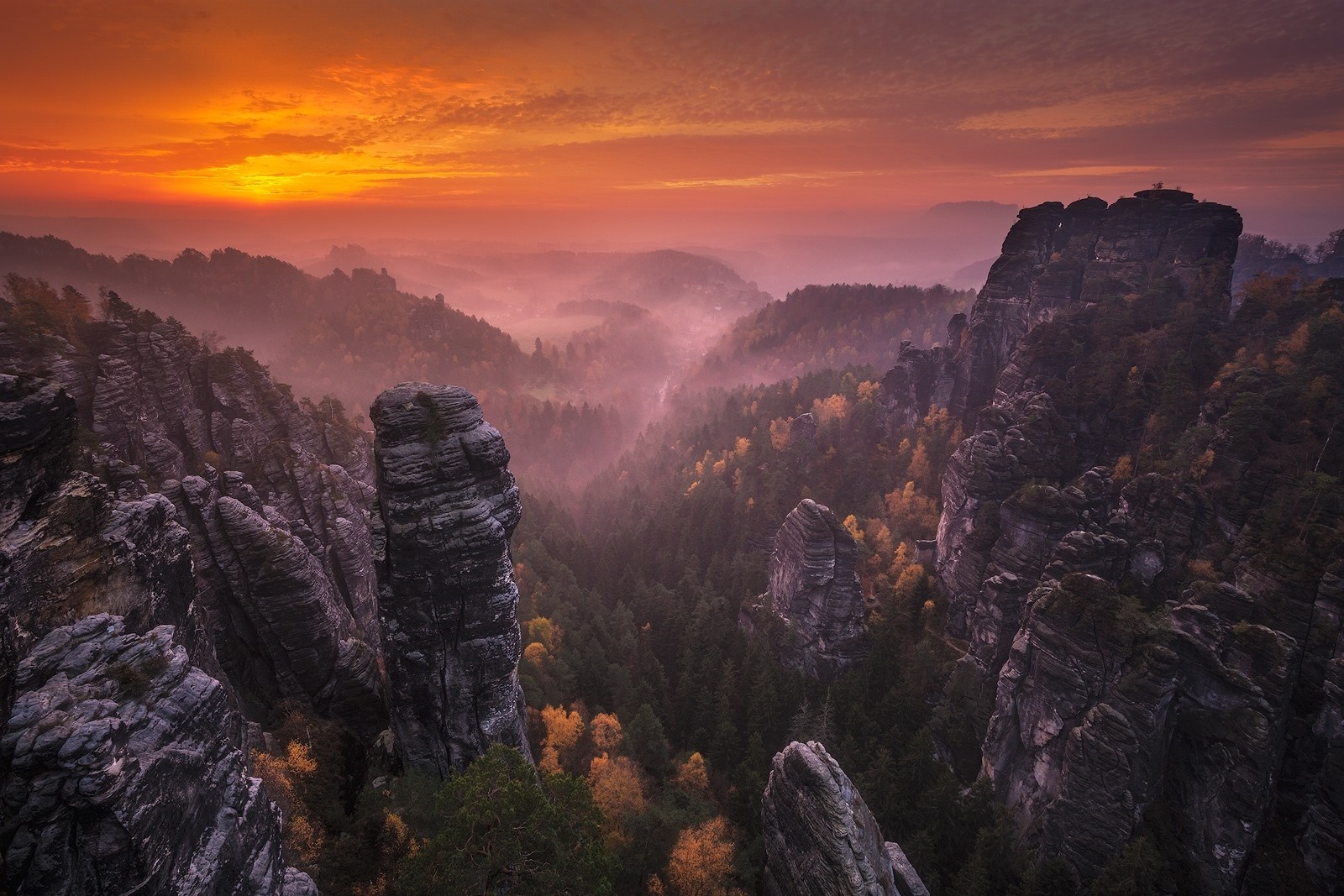 Misty valley with rock formations at sunrise HD Wallpaper