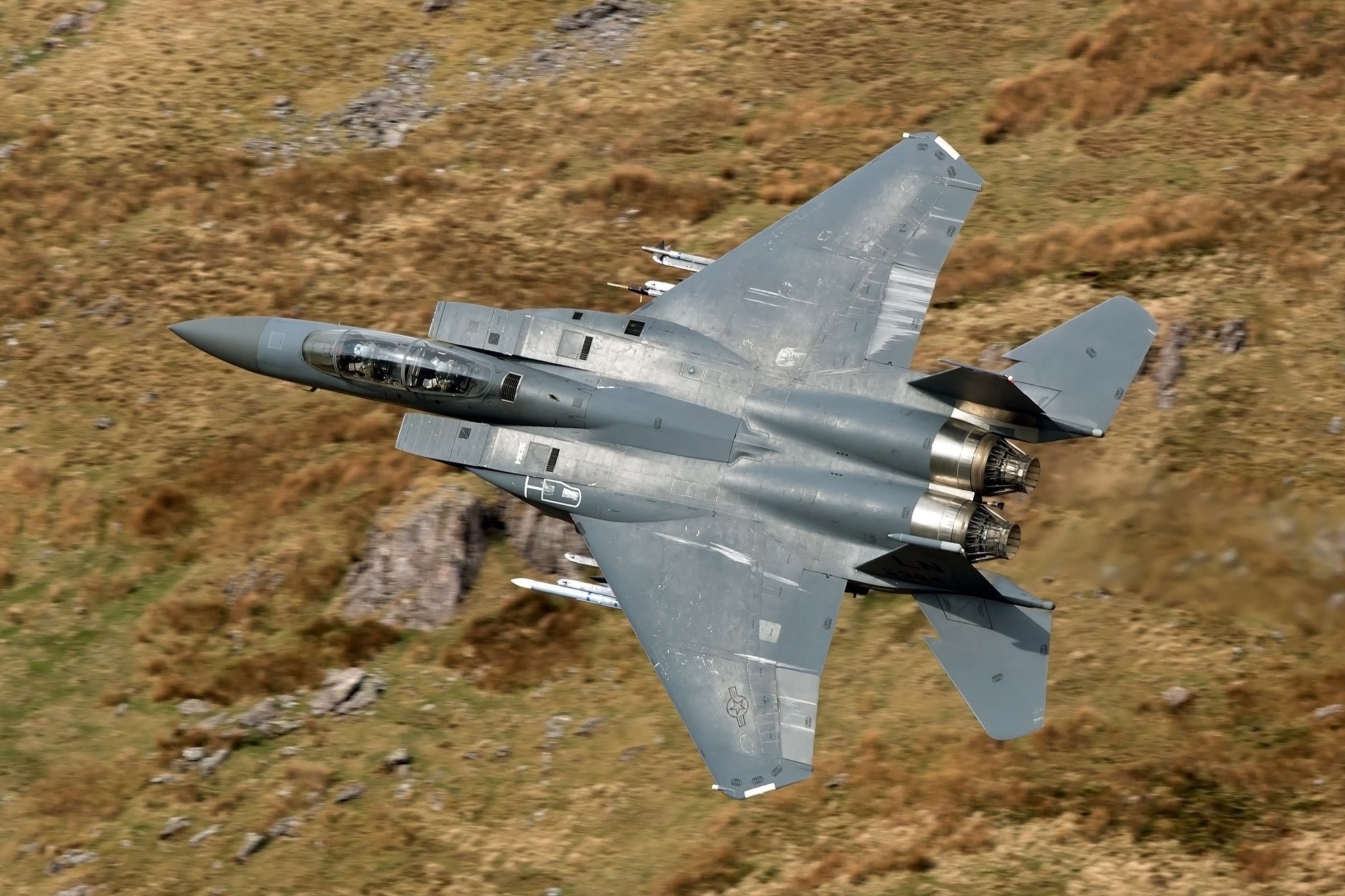 McDonnell Douglas F-15 Eagle fighter jet flying over terrain HD Wallpaper