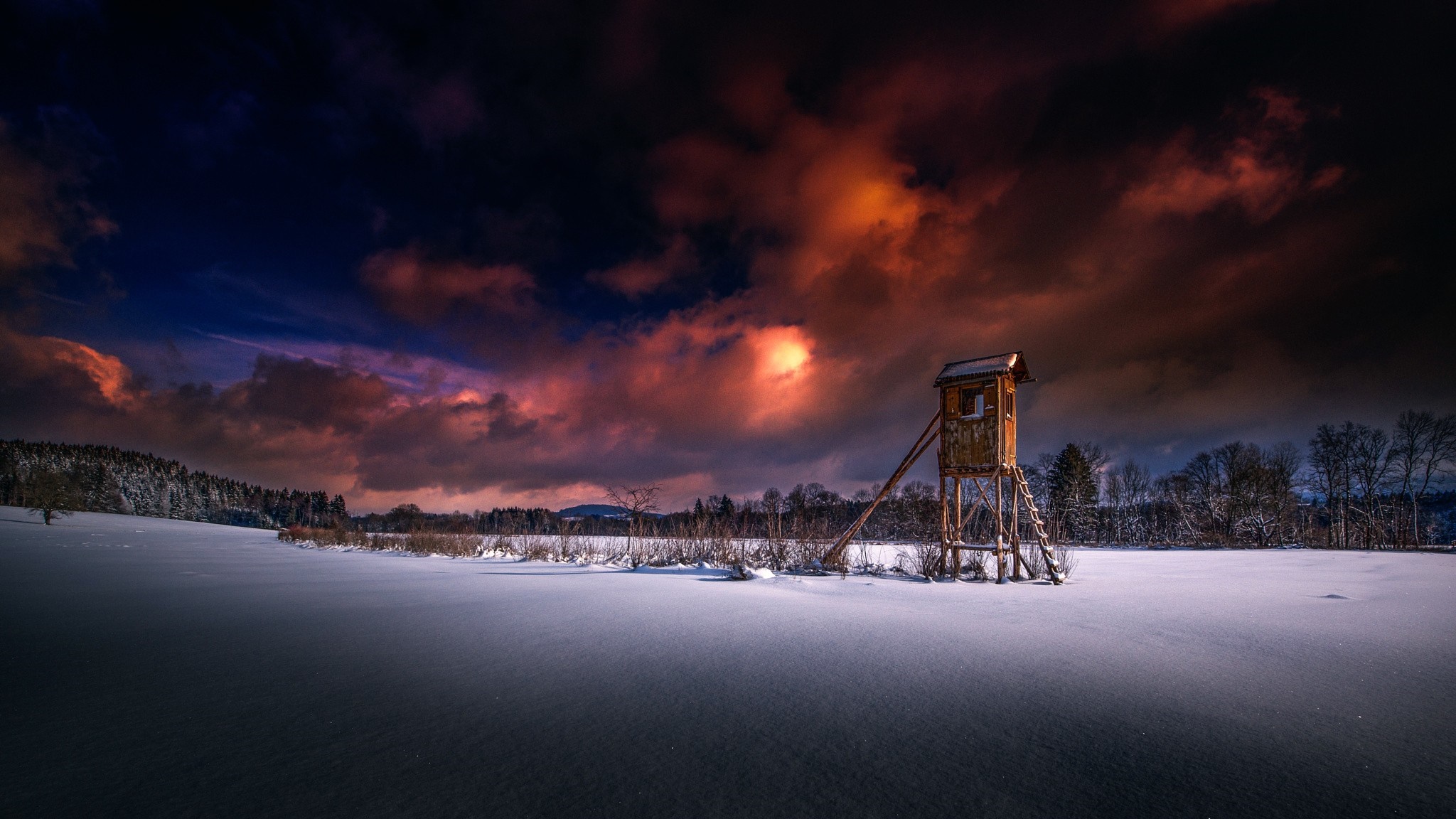 Wooden hunting blind in a snowy landscape at sunset HD Wallpaper