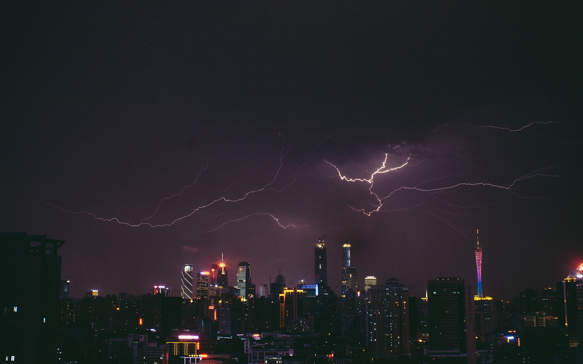 Lightning strikes over a city skyline at night HD Wallpaper
