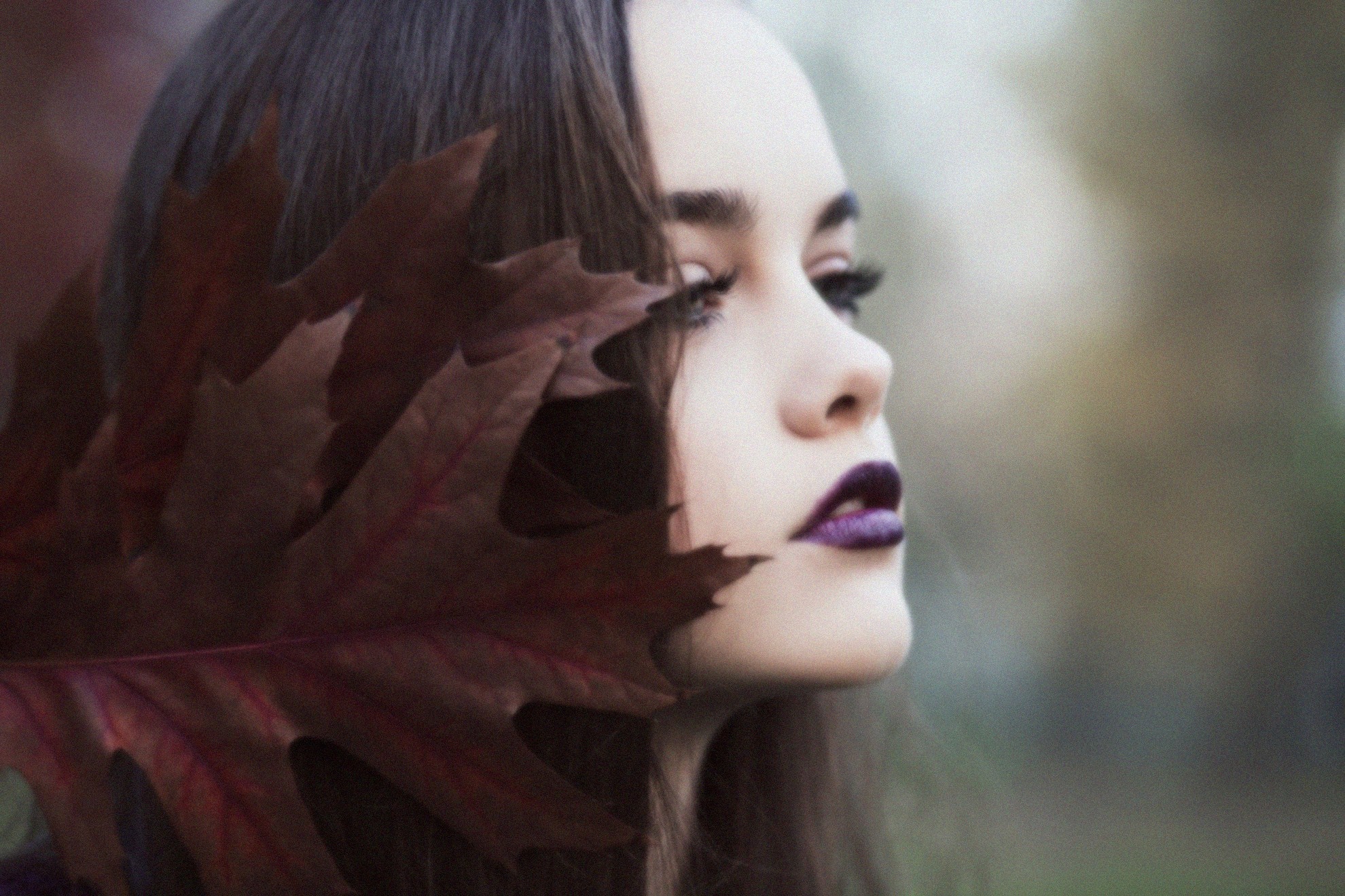 Woman with dark lipstick and leaf covering face HD Wallpaper