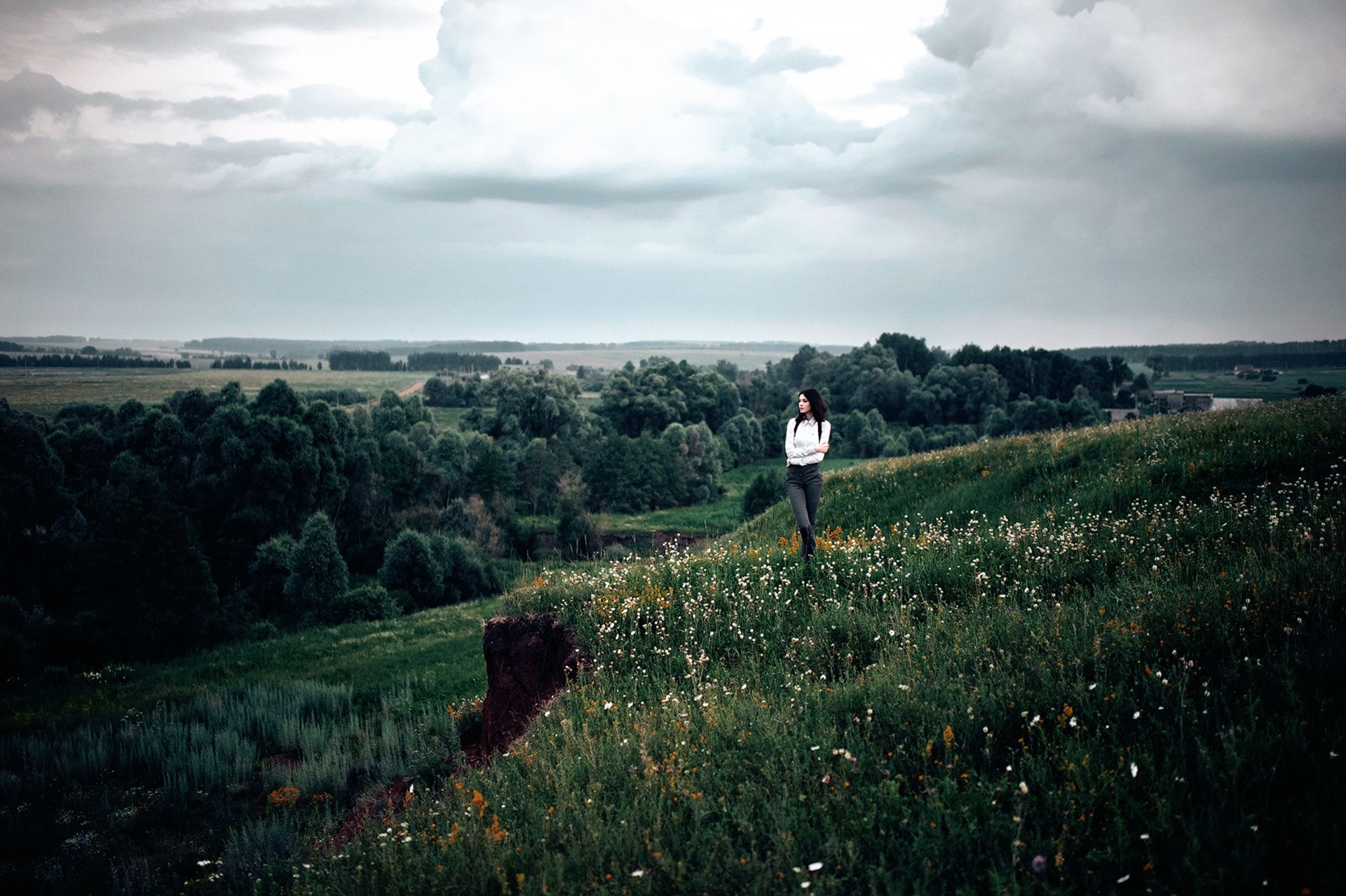 Woman standing on a grassy hill with flowers HD Wallpaper