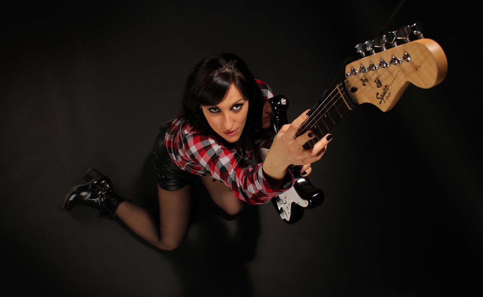 Woman in plaid shirt and leather shorts holding a guitar HD Wallpaper