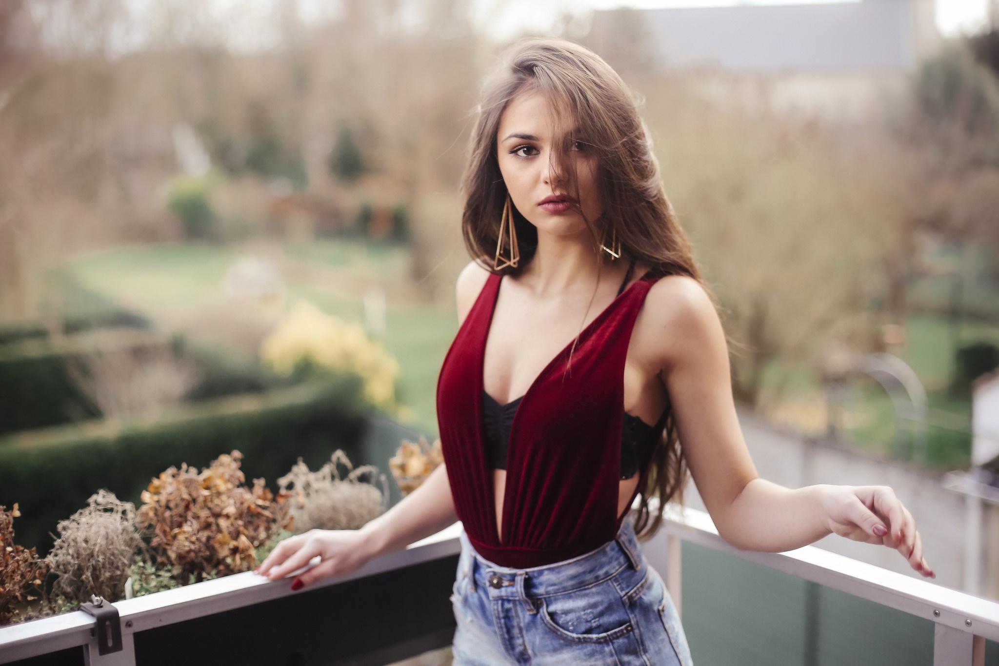 Woman in red velvet bodysuit and denim shorts on balcony HD Wallpaper