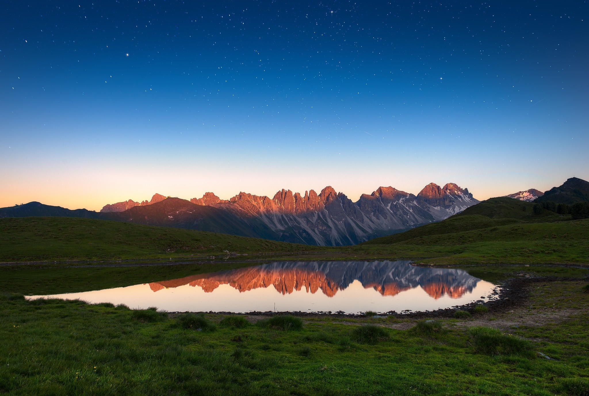 Mountain range reflected in a lake at dusk with stars HD Wallpaper