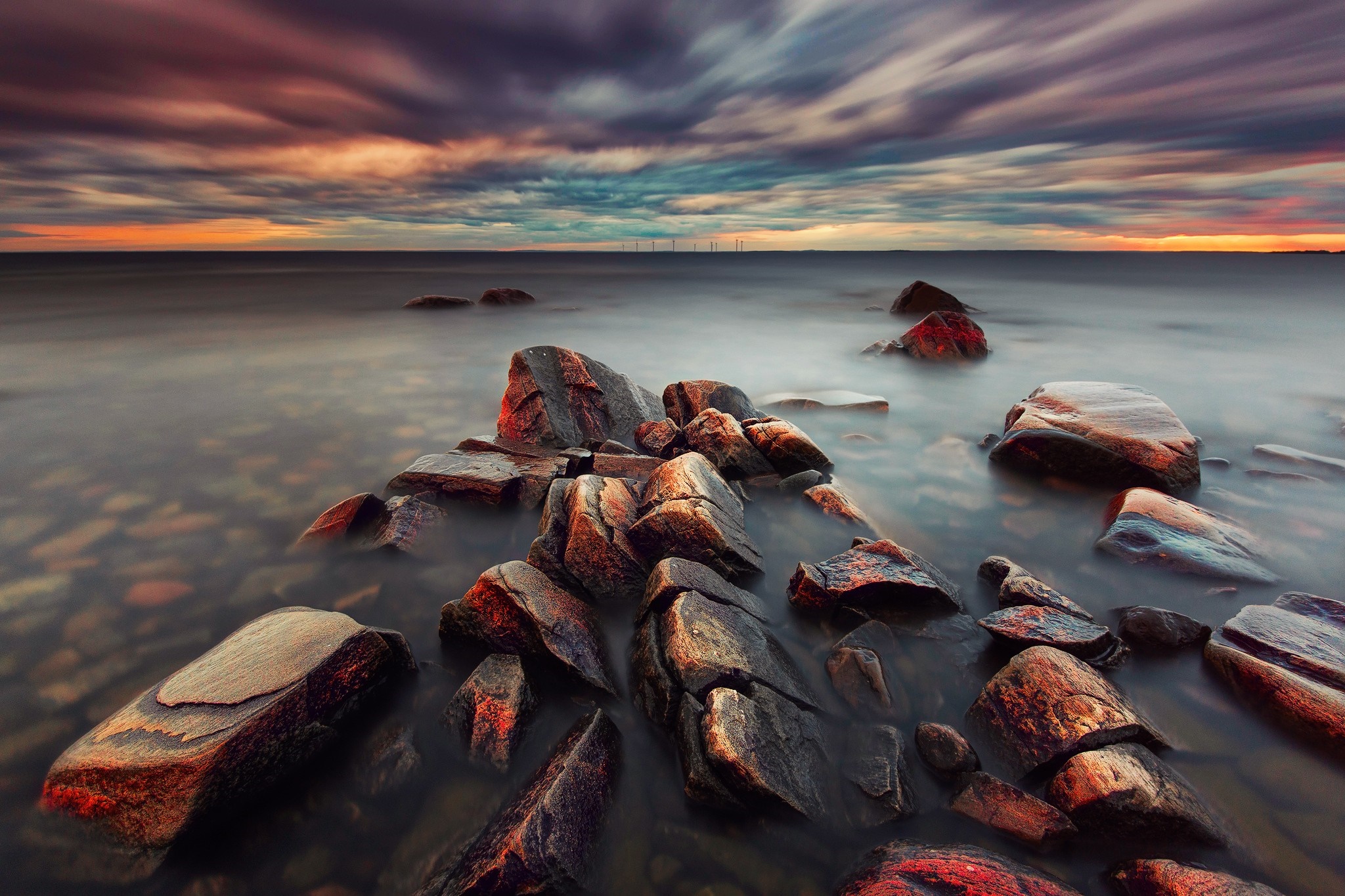 Rocky shore at sunset with colorful clouds over the ocean HD Wallpaper